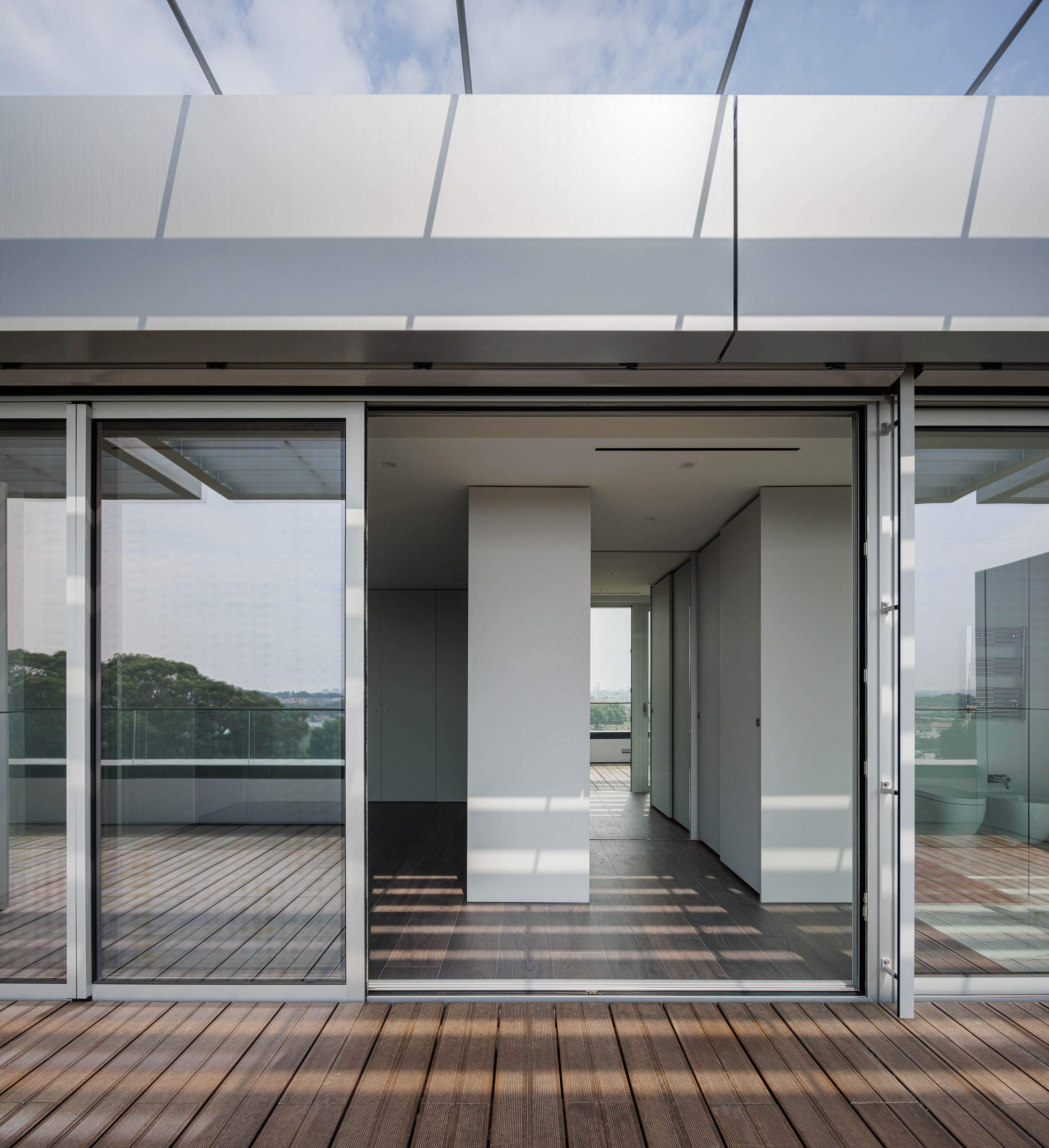 Terraço: Pavimento em madeira e grandes janelas de correr que ligam o interior ao exterior. — Evolution Apartments Housing arquitetura António Paulo Marques, Arquiteto e Associados em Matosinhos