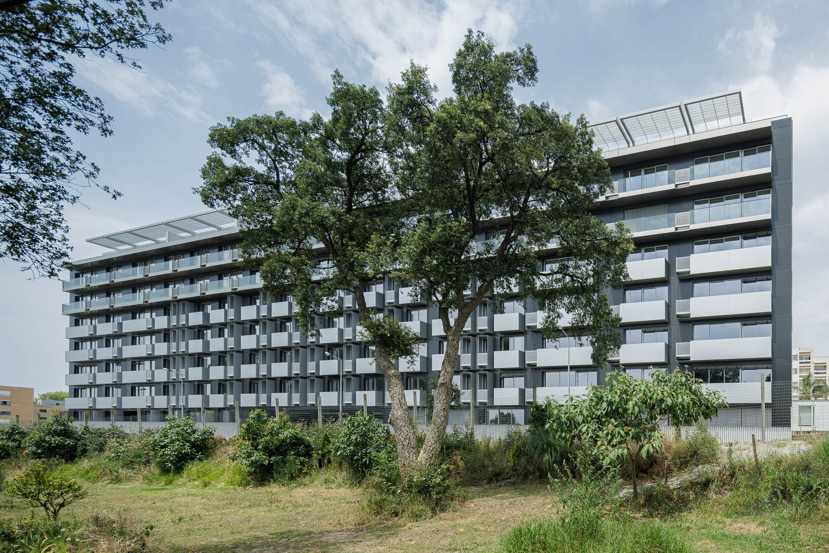 Exterior: Fachada do edifício com varandas em cubo e cobertura com painéis solares. — Evolution Apartments Housing arquitetura António Paulo Marques, Arquiteto e Associados em Matosinhos