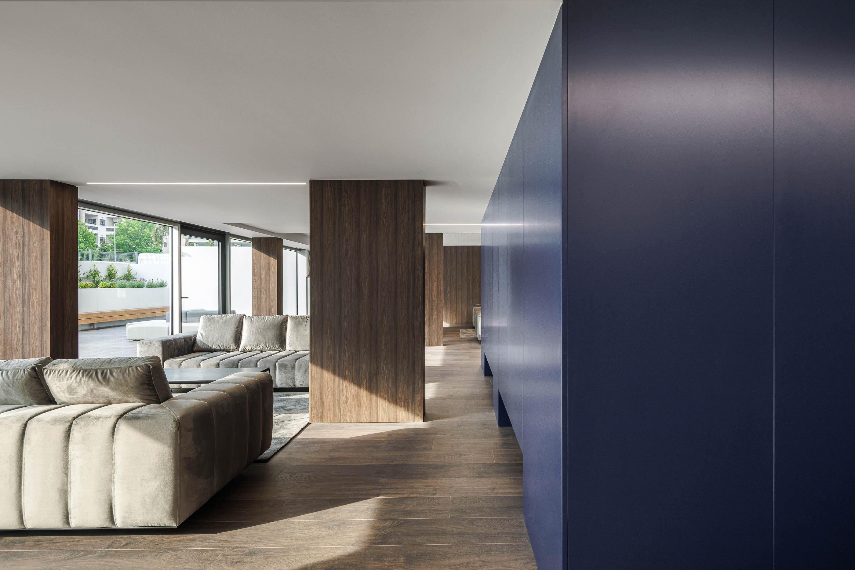 Lobby: Sofás em veludo cinzento, parede azul escura e pavimento em madeira. — Evolution Apartments Housing arquitetura António Paulo Marques, Arquiteto e Associados em Matosinhos