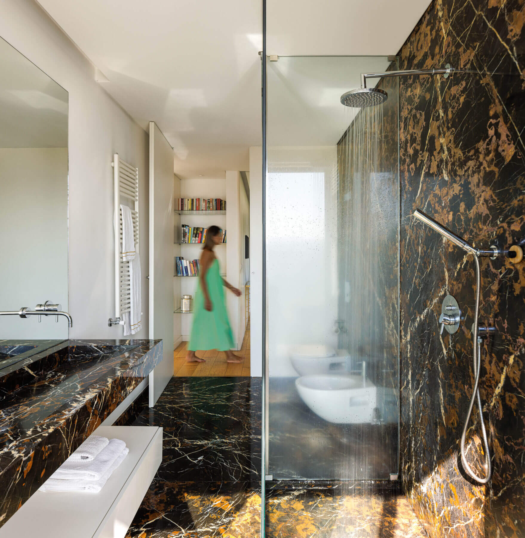 Casa de banho: Pavimento e paredes em mármore escuro, cabine de duche em vidro, lavatório em mármore e sanitários brancos. — Casa do Alto arquitetura Jorge Martins arquiteto em Celorico de Basto
