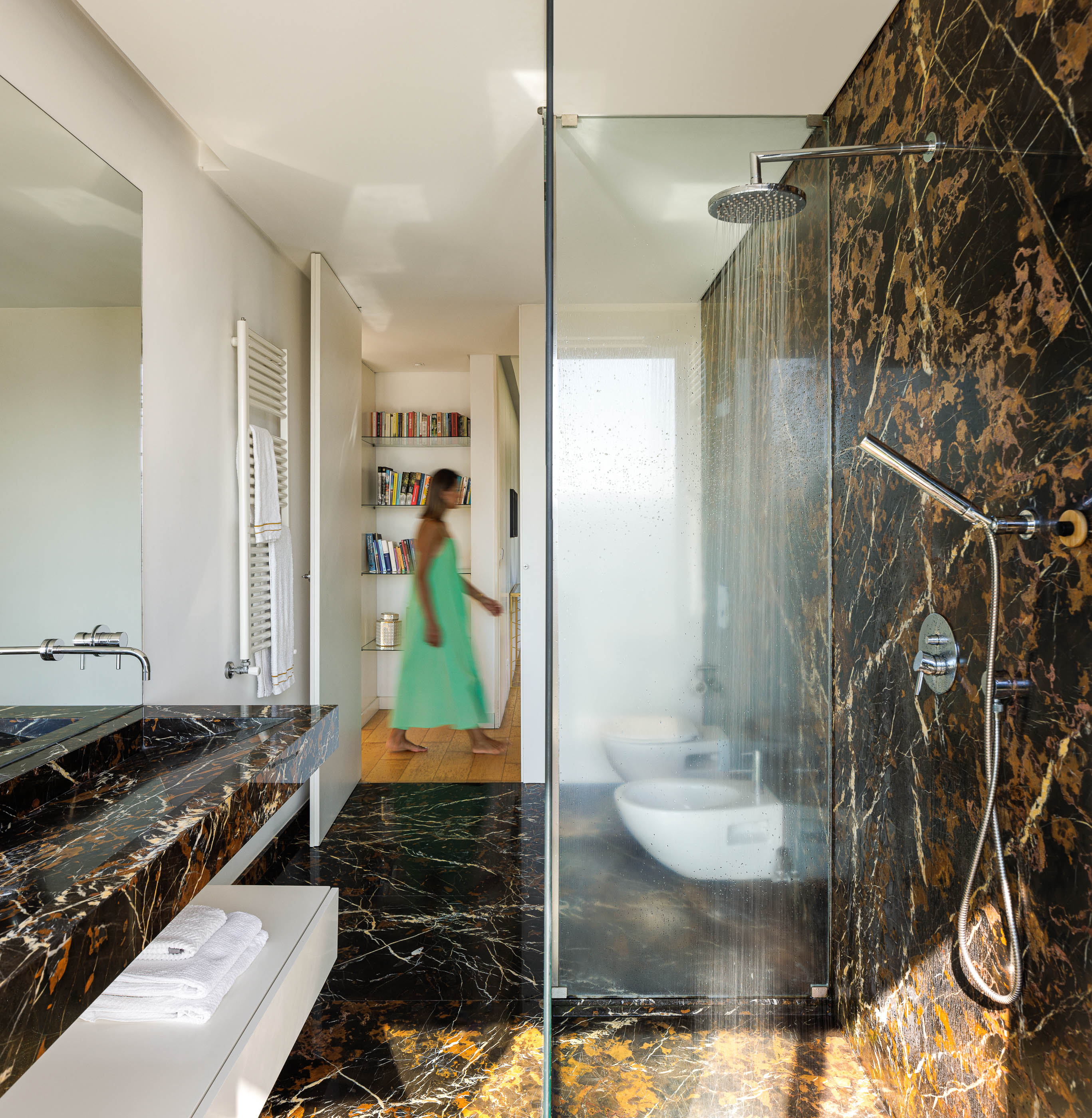 Casa de banho: Pavimento e paredes em mármore escuro, cabine de duche em vidro, lavatório em mármore e sanitários brancos. — Casa do Alto arquitetura Jorge Martins arquiteto em Celorico de Basto