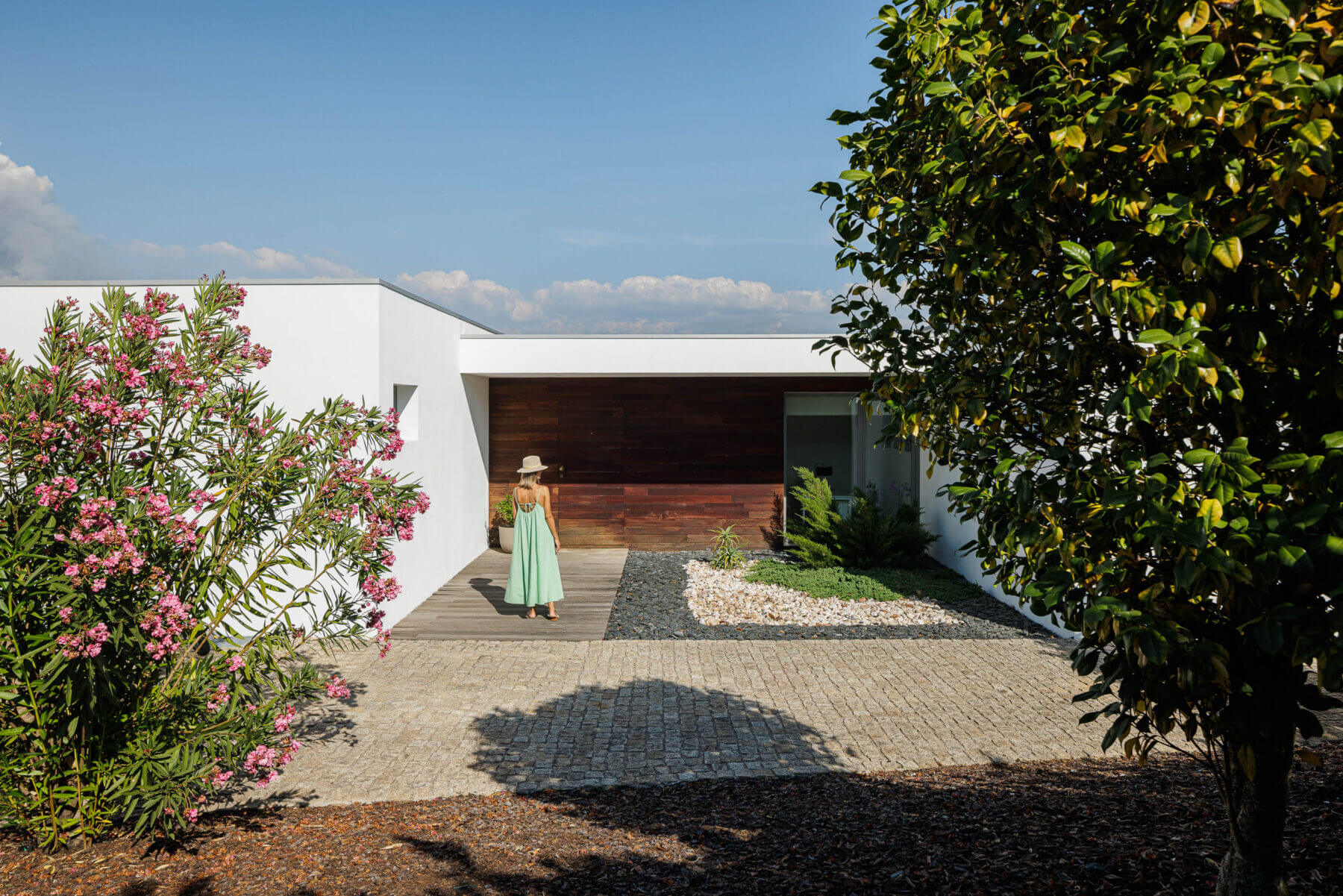 Exterior: Fachada branca com detalhes em madeira, jardim com vegetação e caminho em calçada portuguesa. — Casa do Alto arquitetura Jorge Martins arquiteto em Celorico de Basto