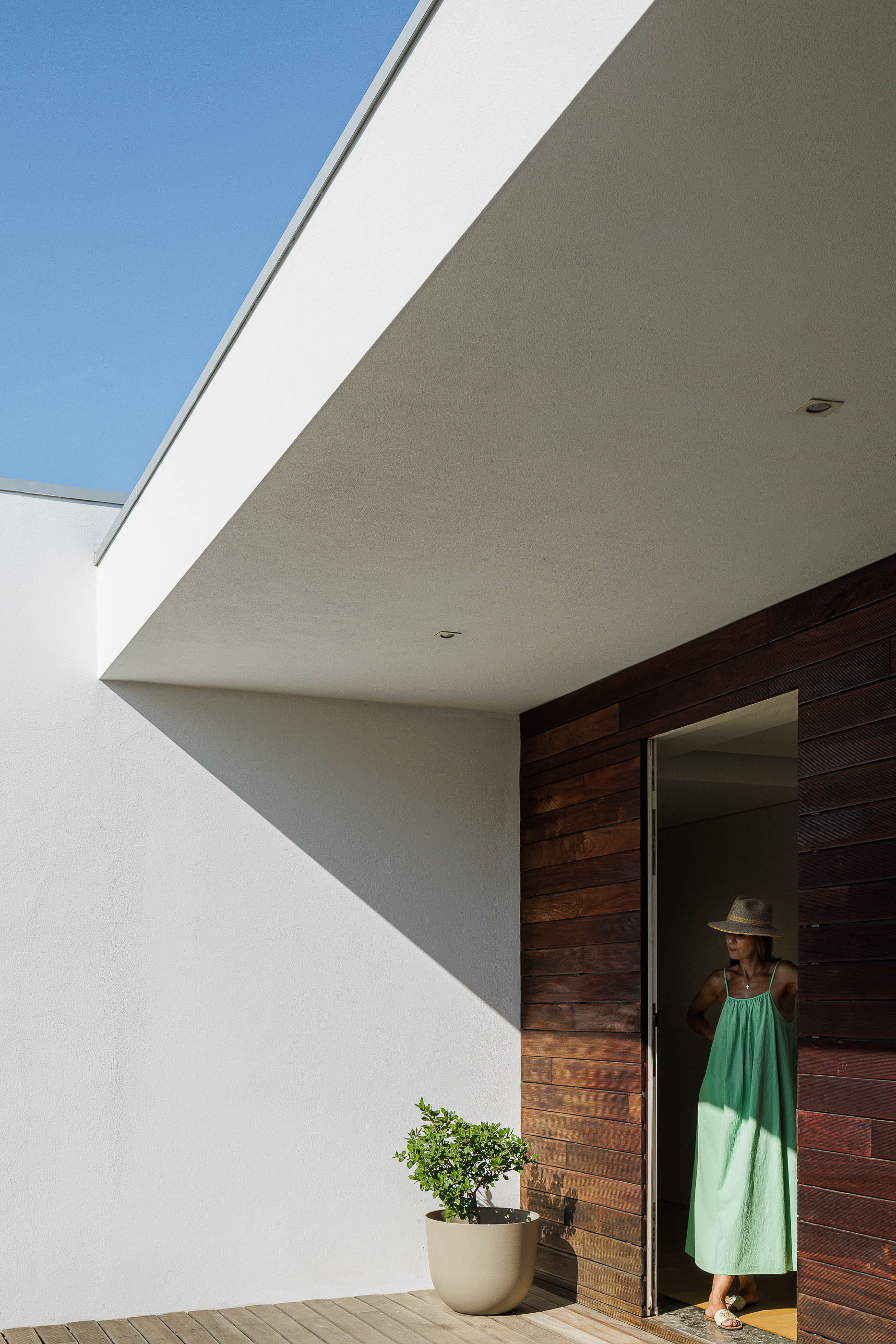 Entrada: Fachada em madeira escura, porta de entrada aberta e pavimento em deck de madeira. — Casa do Alto arquitetura Jorge Martins arquiteto em Celorico de Basto