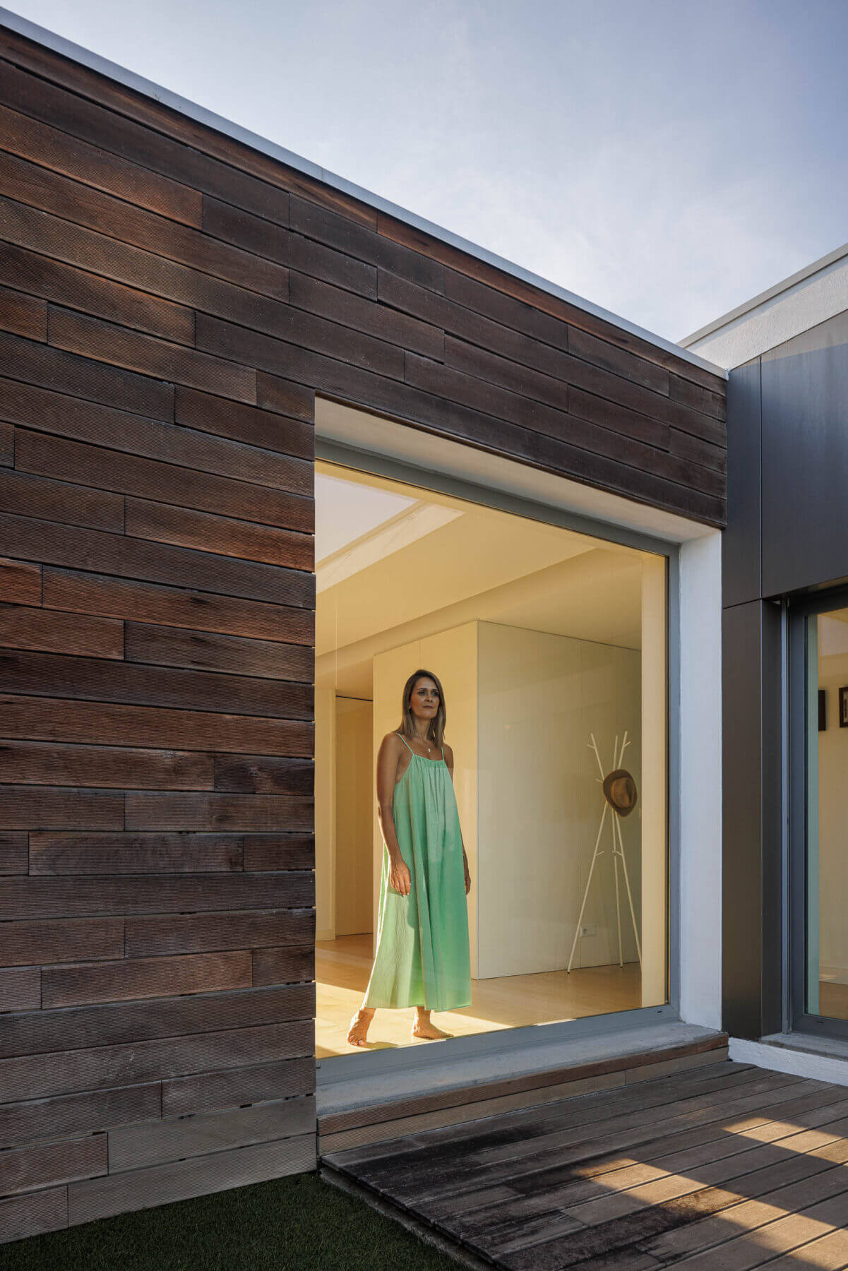 Exterior: Fachada em madeira escura, janela com vista para o interior e deck de madeira. — Casa do Alto arquitetura Jorge Martins arquiteto em Celorico de Basto