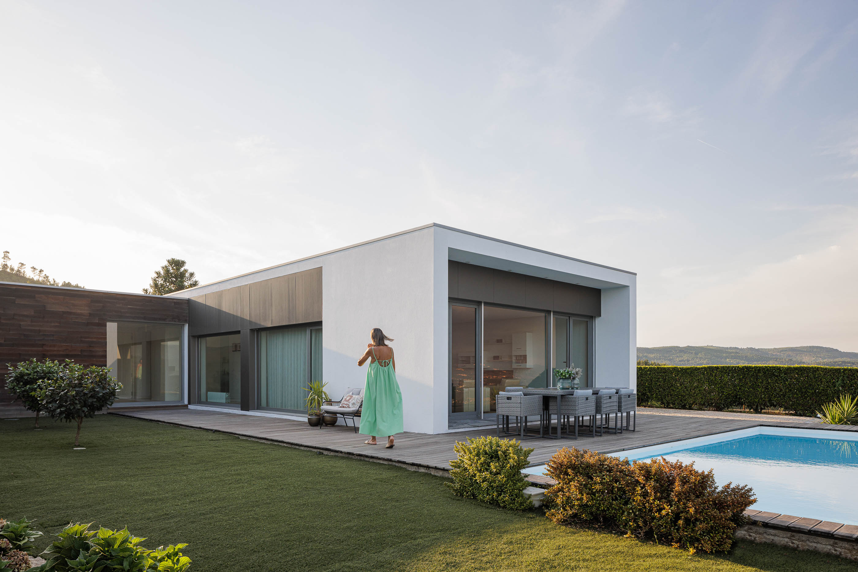 Exterior: Vista geral da casa com piscina, pátio interior, fachada em madeira e volumes brancos. — Casa do Alto arquitetura Jorge Martins arquiteto em Celorico de Basto