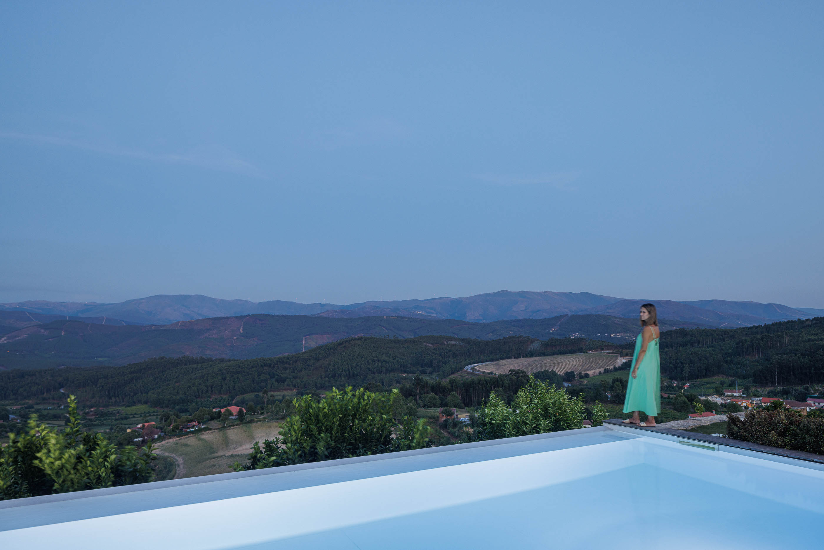 Exterior: Piscina com borda infinita e vista panorâmica ao entardecer. — Casa do Alto arquitetura Jorge Martins arquiteto em Celorico de Basto