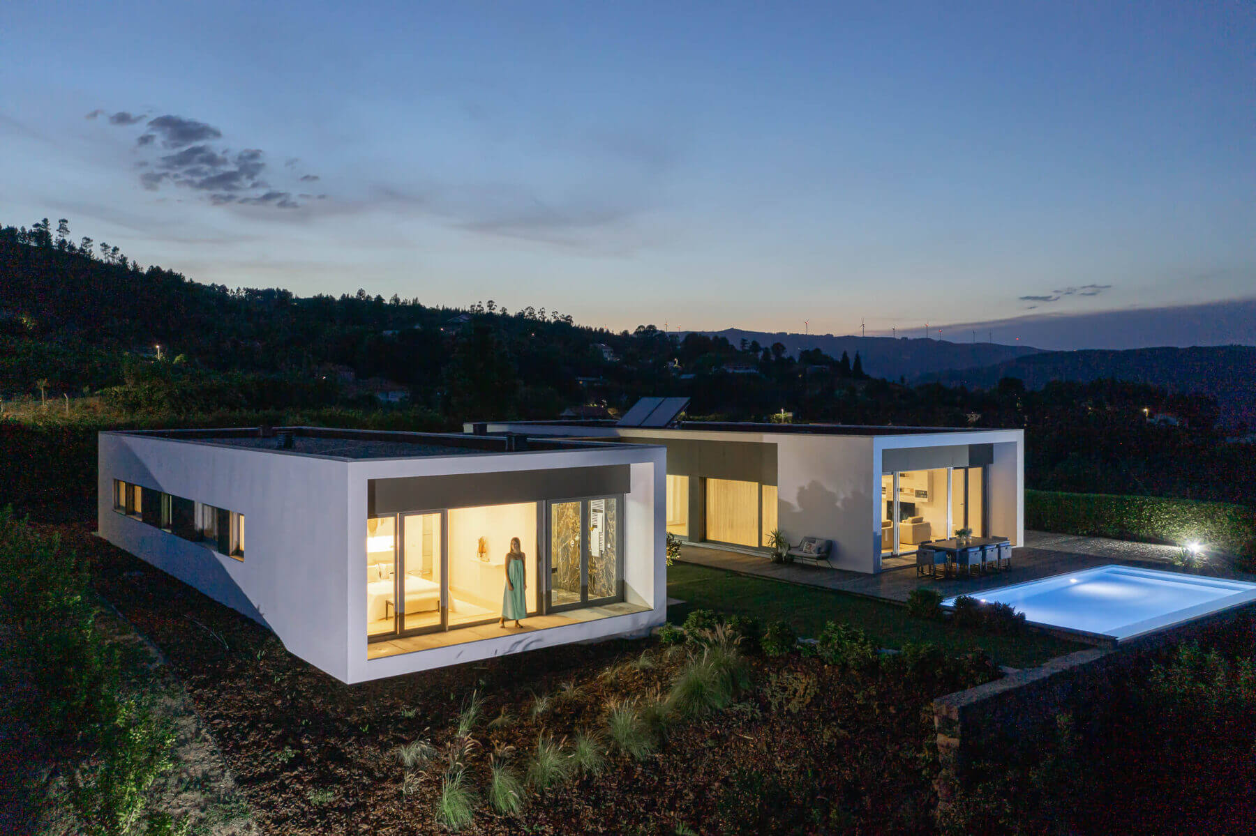 Exterior: Vista noturna da casa com piscina, pátio interior e fachadas iluminadas. — Casa do Alto arquitetura Jorge Martins arquiteto em Celorico de Basto