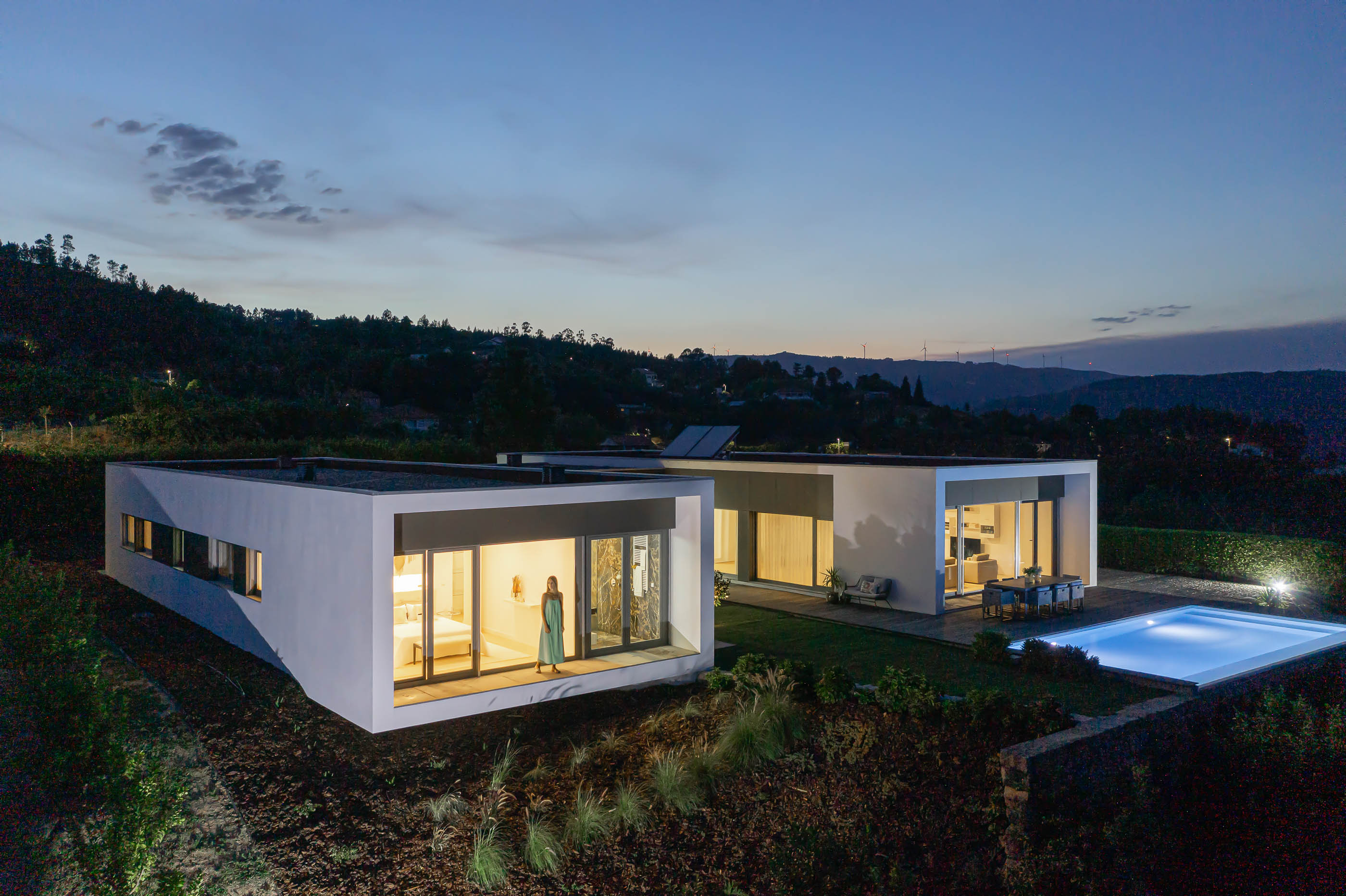 Exterior: Vista noturna da casa com piscina, pátio interior e fachadas iluminadas. — Casa do Alto arquitetura Jorge Martins arquiteto em Celorico de Basto