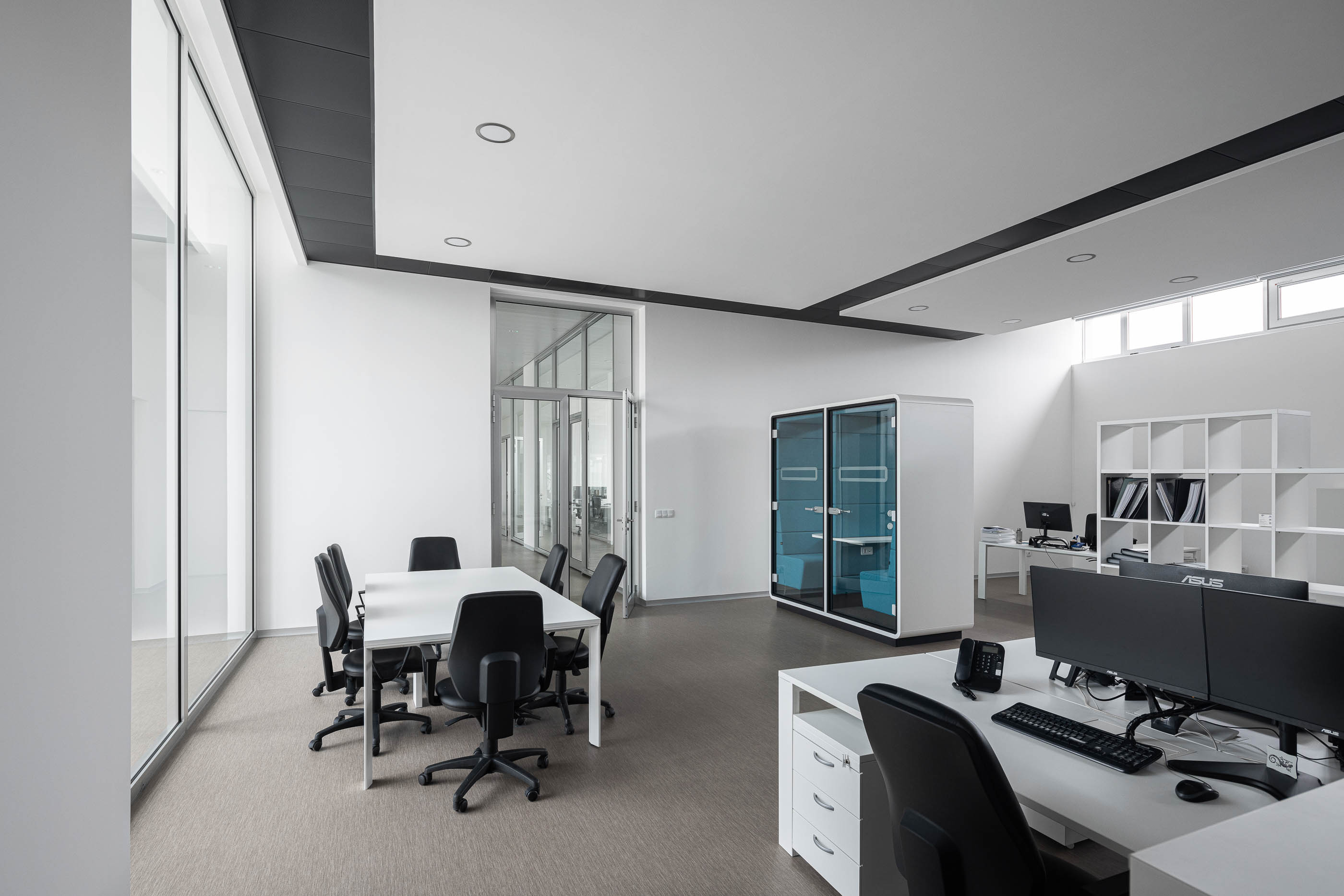 Escritório com mesa de reuniões, secretárias brancas e armário azul. Pavimento cinzento. — Edifício Sede da PRF arquitetura Impare Arquitectura em Leiria