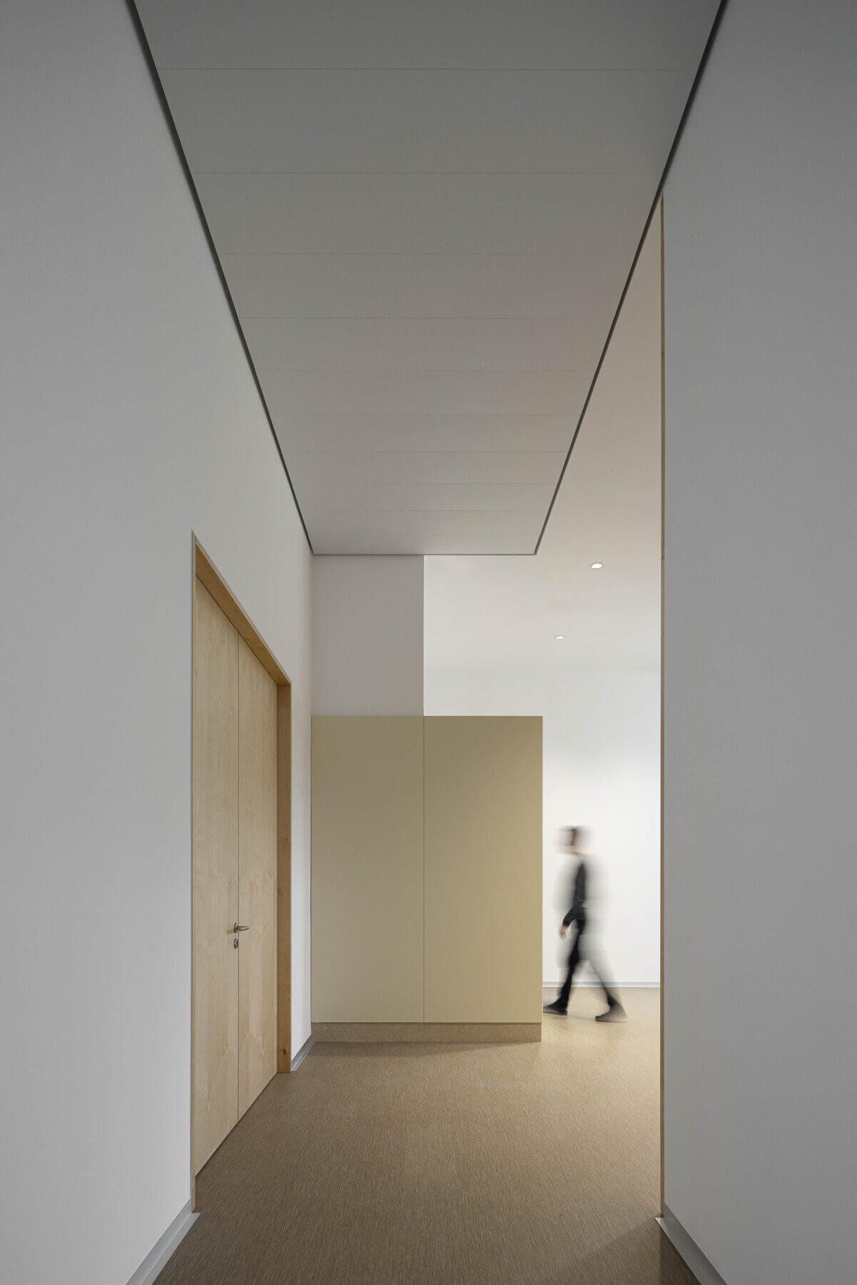 Corredor com paredes brancas e portas de madeira clara. Pavimento em tons de bege. — Edifício Sede da PRF arquitetura Impare Arquitectura em Leiria
