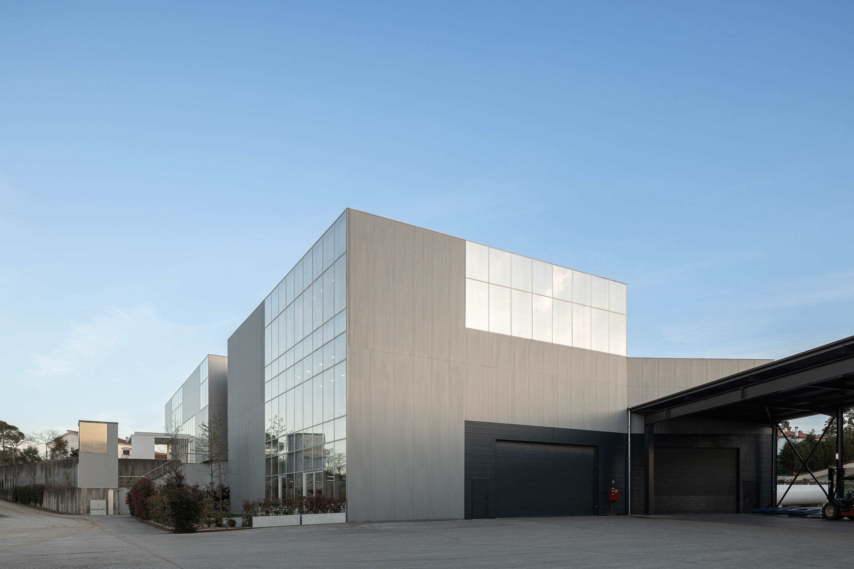Vista exterior do edifício com fachada cinzenta e janelas amplas. — Edifício Sede da PRF arquitetura Impare Arquitectura em Leiria