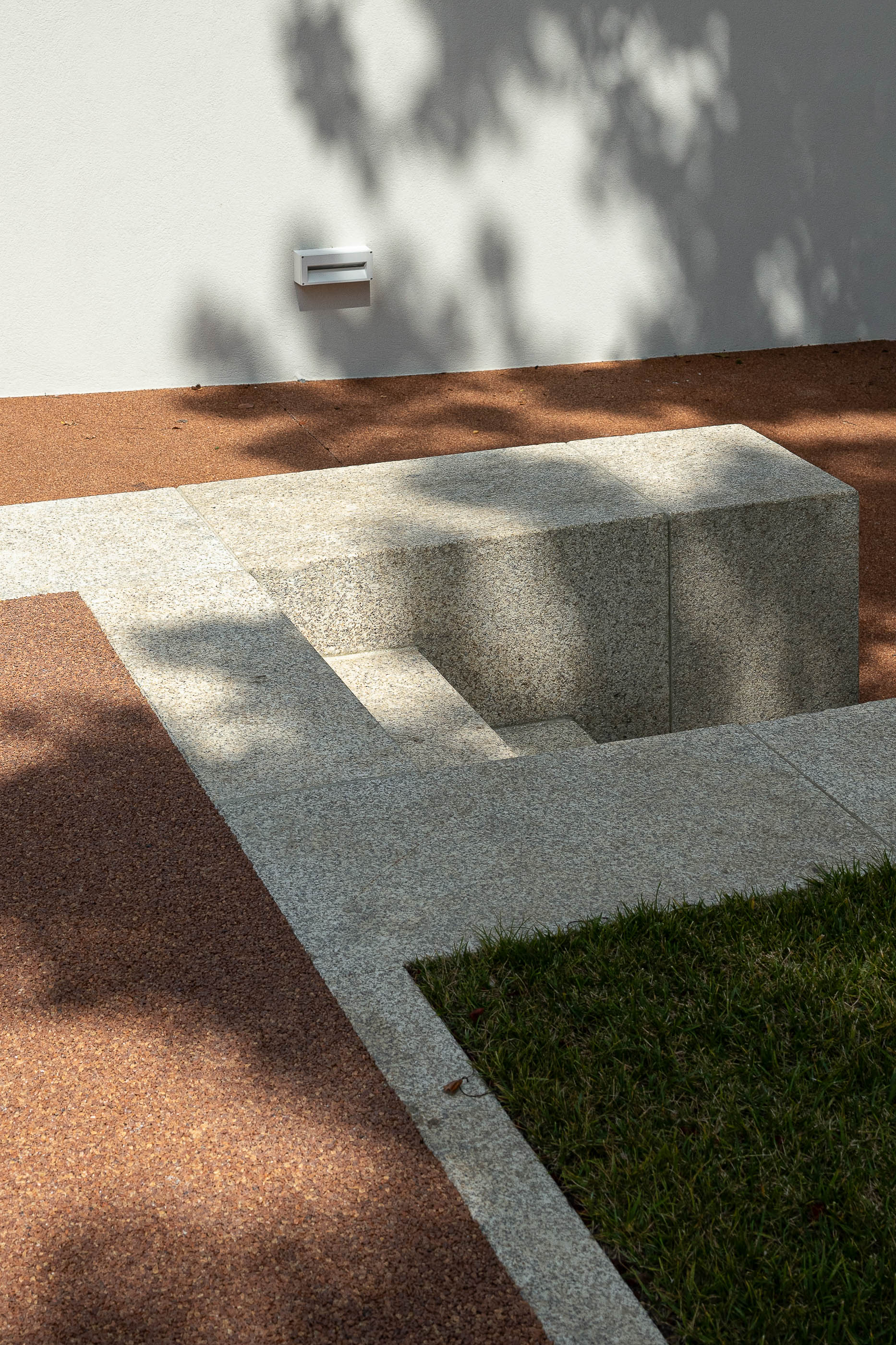 Jardim: Detalhe de escadas em granito, pavimento em cortiça e relvado, com sombra de árvore. — Casa IMLA arquitetura Luppa em Porto