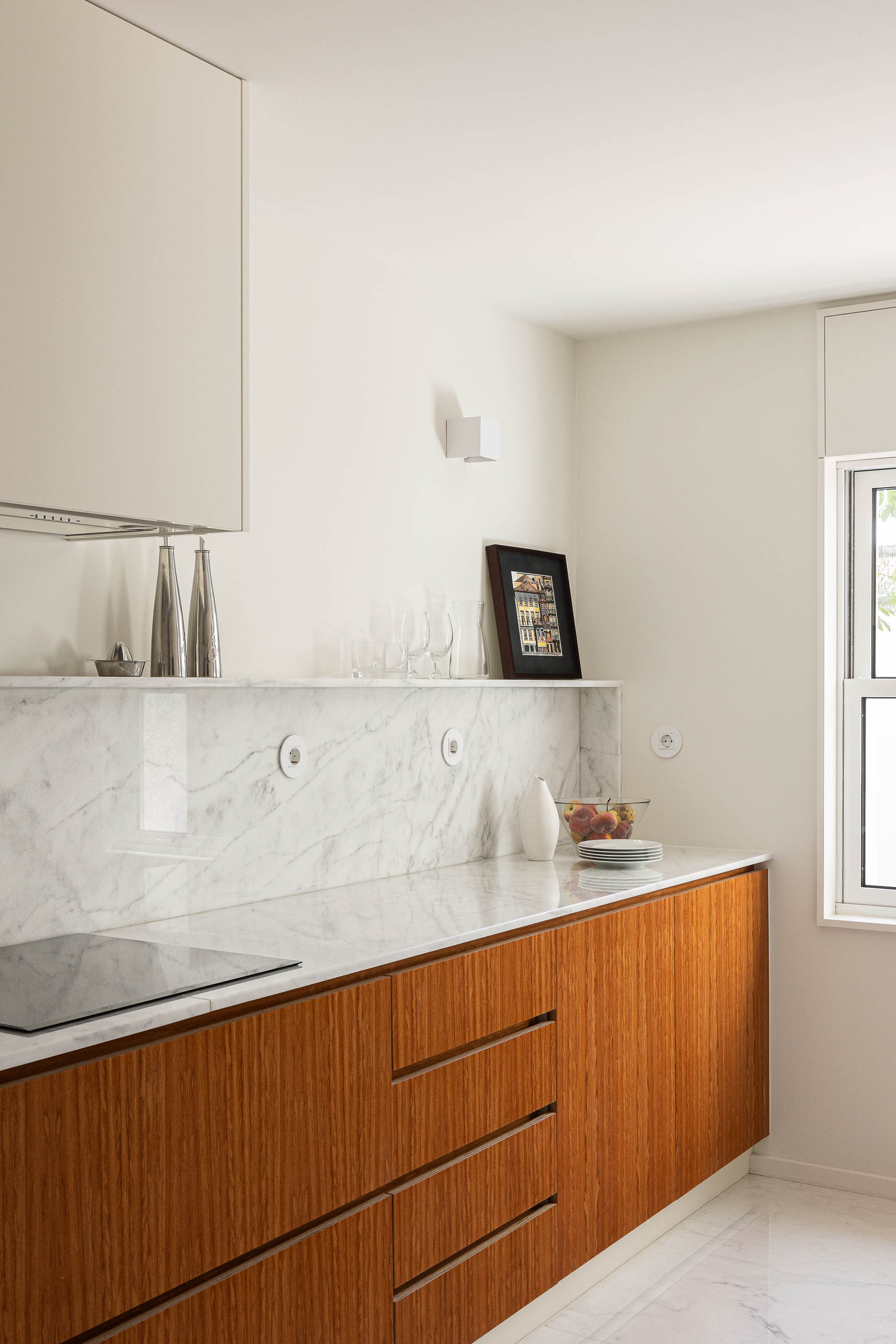 Cozinha: Bancada em madeira com tampo em mármore, armários brancos e pavimento em mármore. — Casa IMLA arquitetura Luppa em Porto