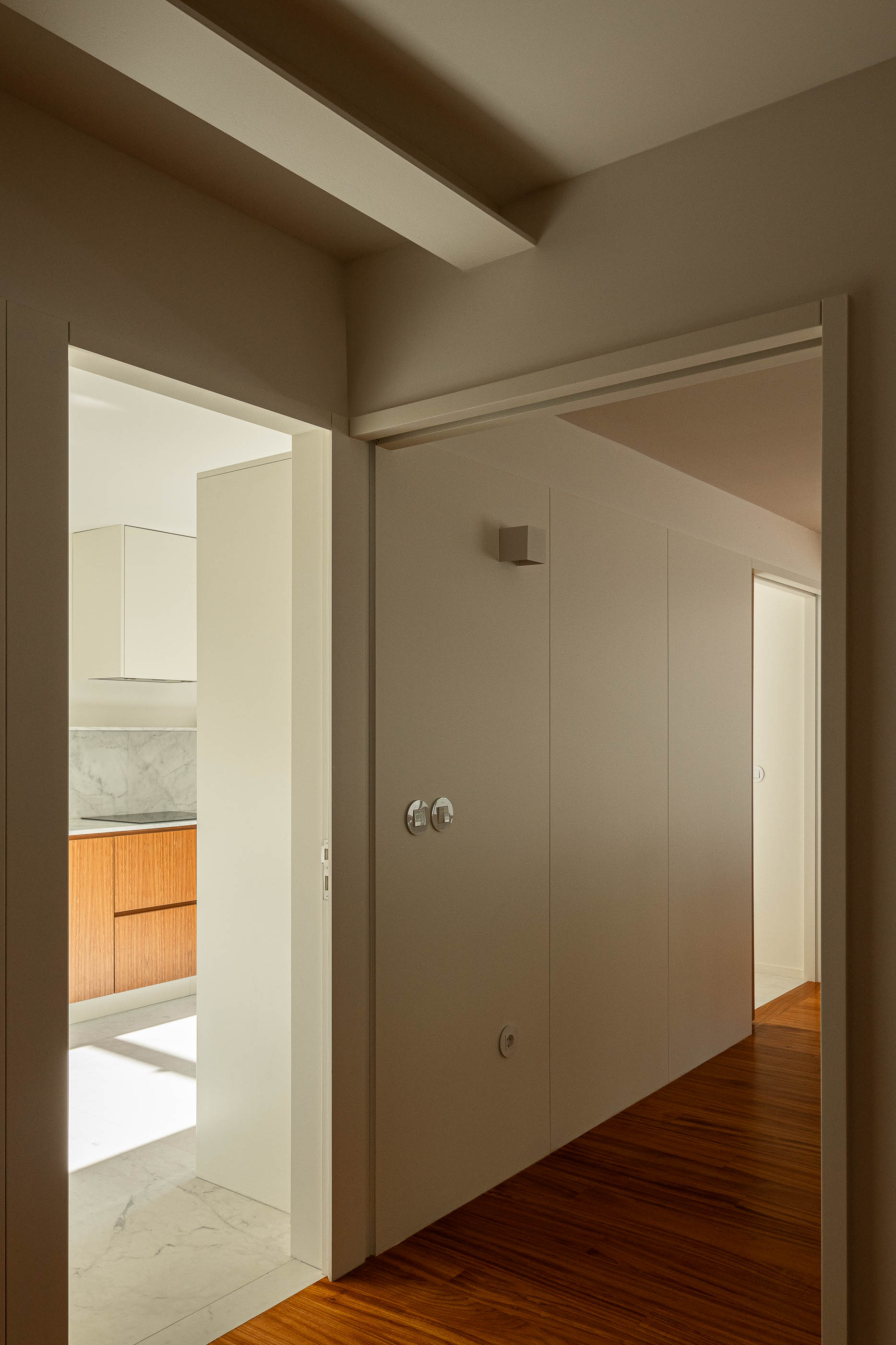 Corredor: Vista da cozinha com bancada em madeira e mármore, pavimento em mármore. — Casa IMLA arquitetura Luppa em Porto