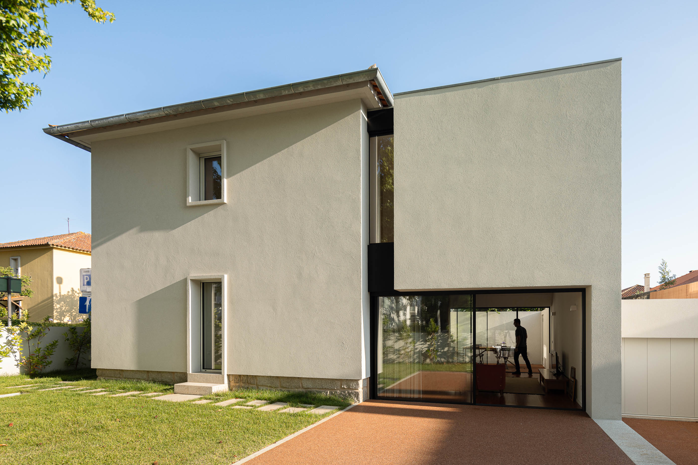 Exterior: Fachada da casa com detalhes em preto, jardim relvado e pavimento em cortiça. — Casa IMLA arquitetura Luppa em Porto
