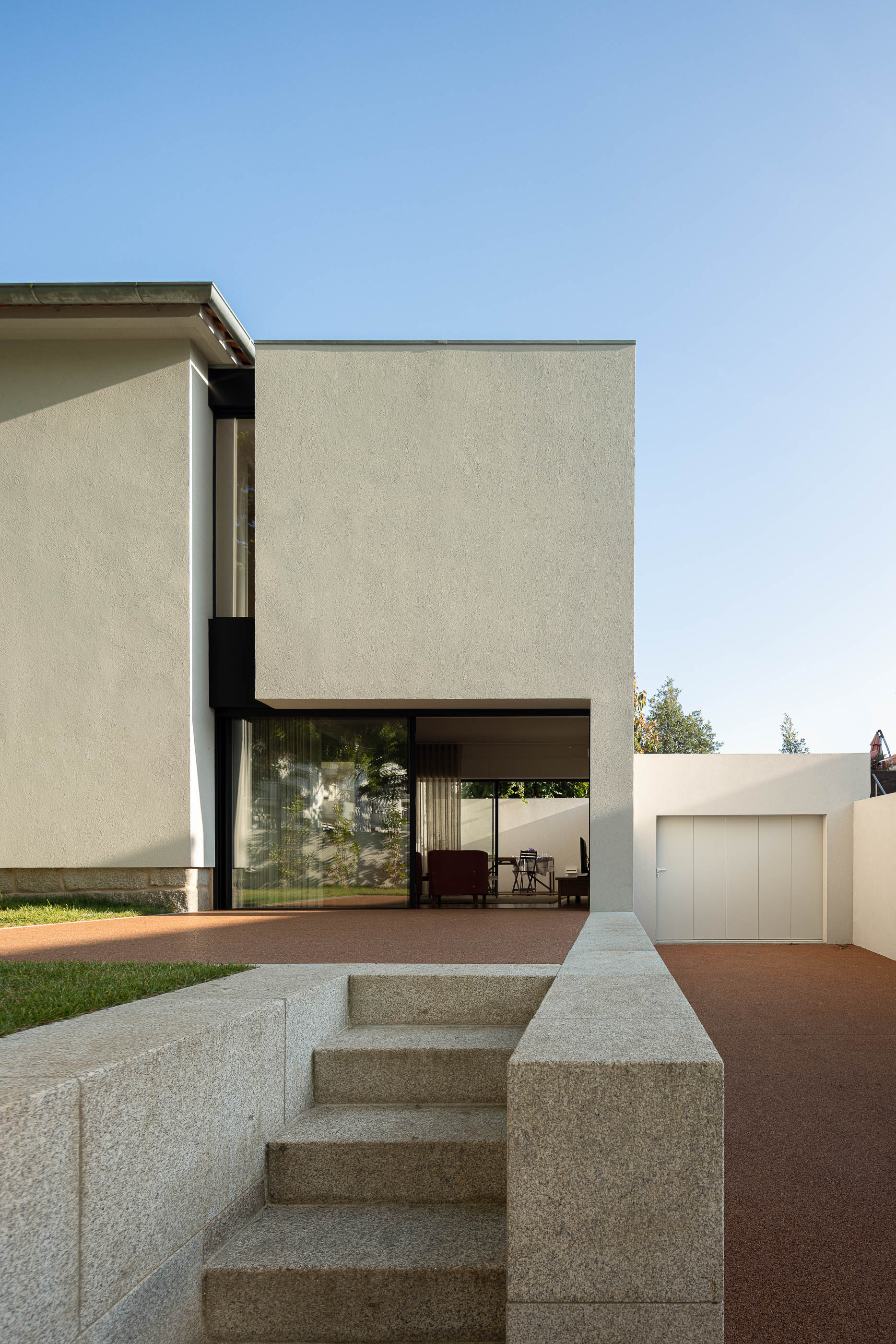 Exterior: Escadas em granito, fachada da casa com detalhes em preto, jardim e garagem. — Casa IMLA arquitetura Luppa em Porto