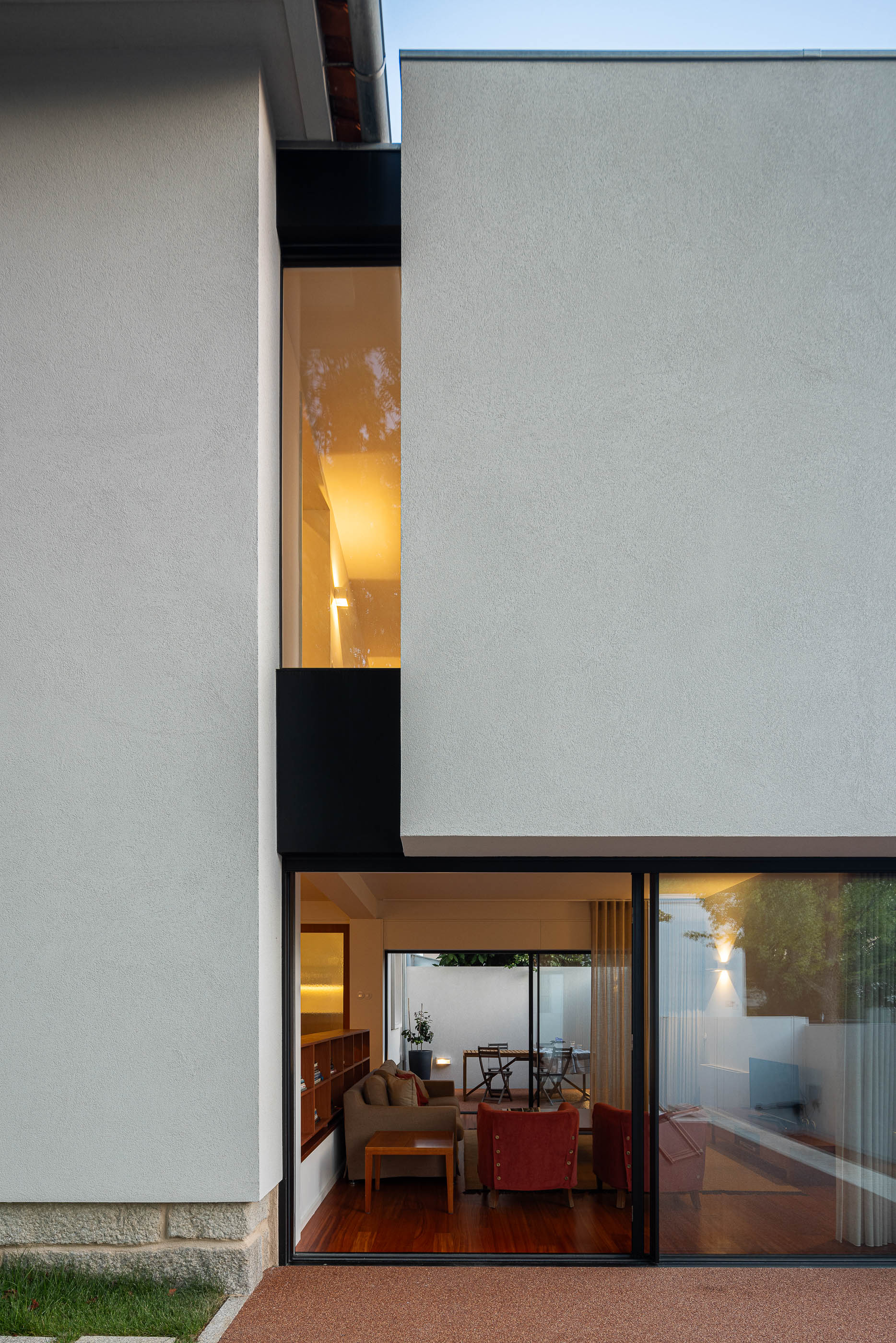 Exterior: Fachada da casa com detalhes em preto, vista da sala de estar e pátio. — Casa IMLA arquitetura Luppa em Porto