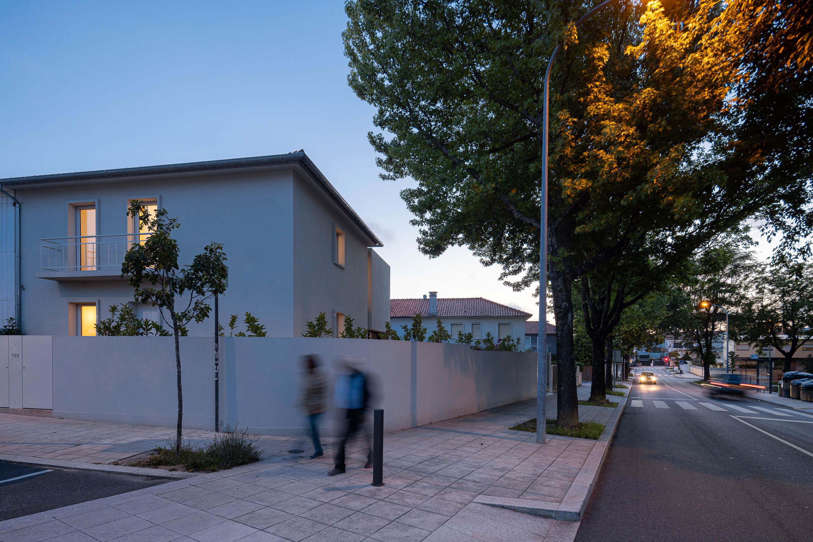 Exterior: Vista noturna da casa a partir da rua, com iluminação pública e vegetação. — Casa IMLA arquitetura Luppa em Porto