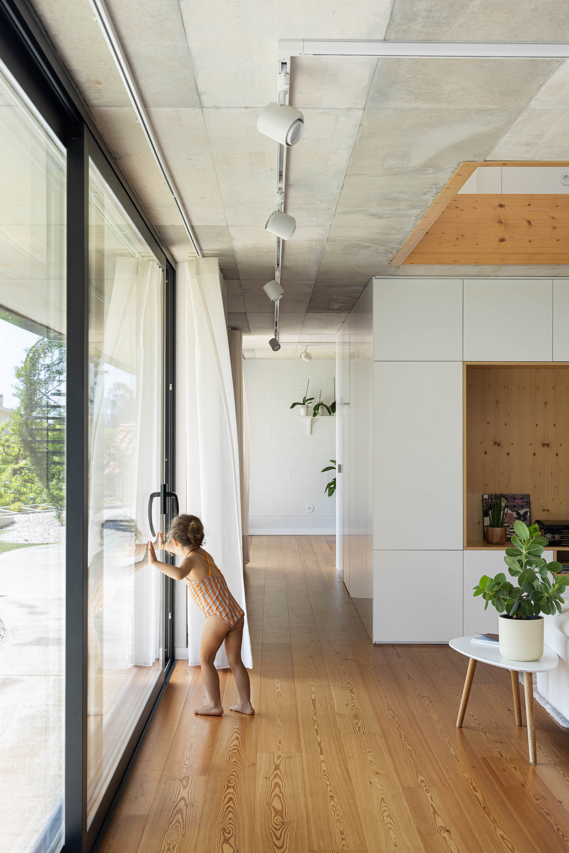 Sala de estar: Vista da sala de estar com piano branco, pavimento de madeira e entrada com mosaico preto. — Casa do Sobreiro arquitetura Skemba - Arquitectura e Engenharia em Amarante