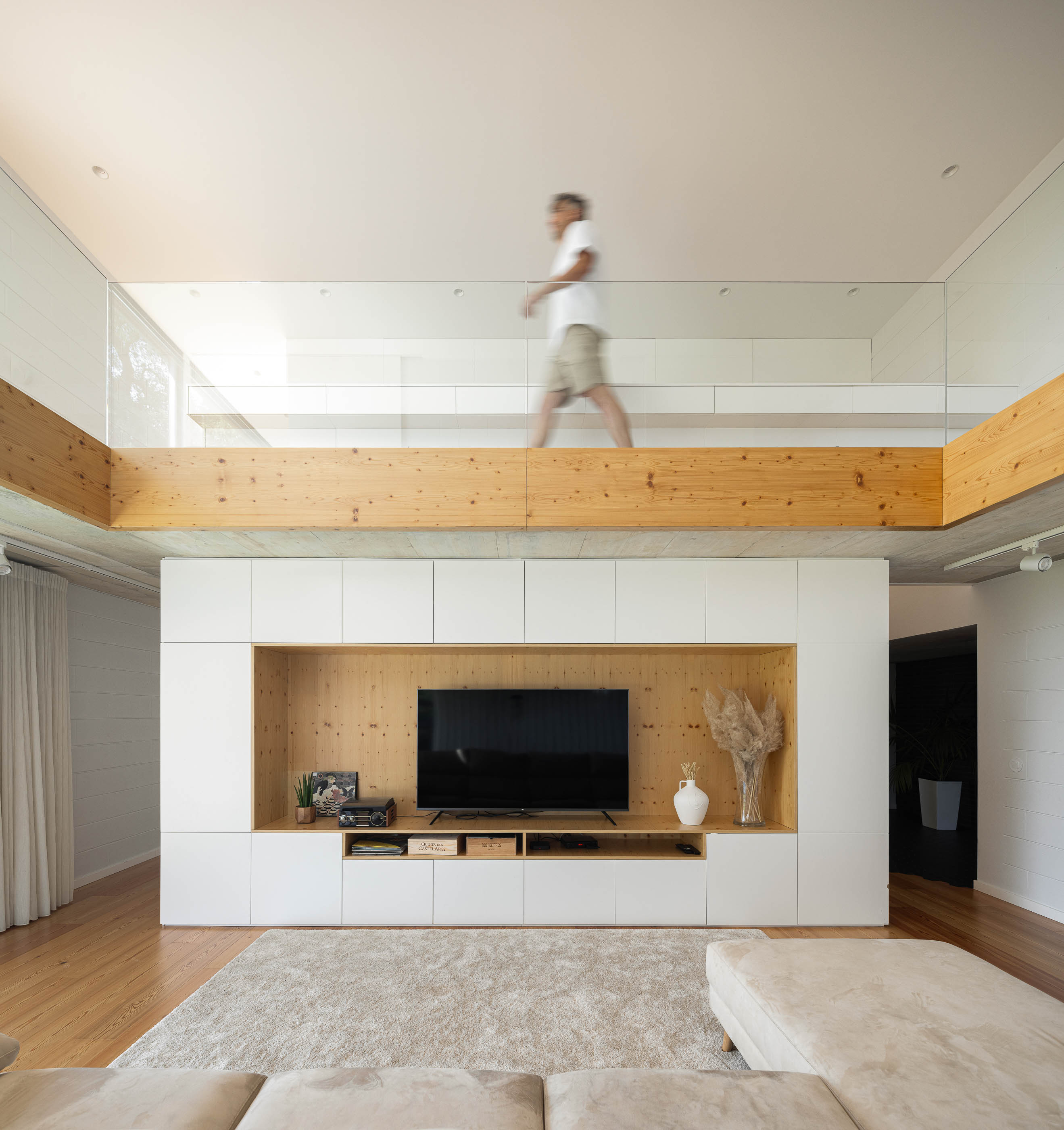 Sala de estar: Vista da sala de estar com janelas amplas, pavimento de madeira e jardim com relvado. — Casa do Sobreiro arquitetura Skemba - Arquitectura e Engenharia em Amarante