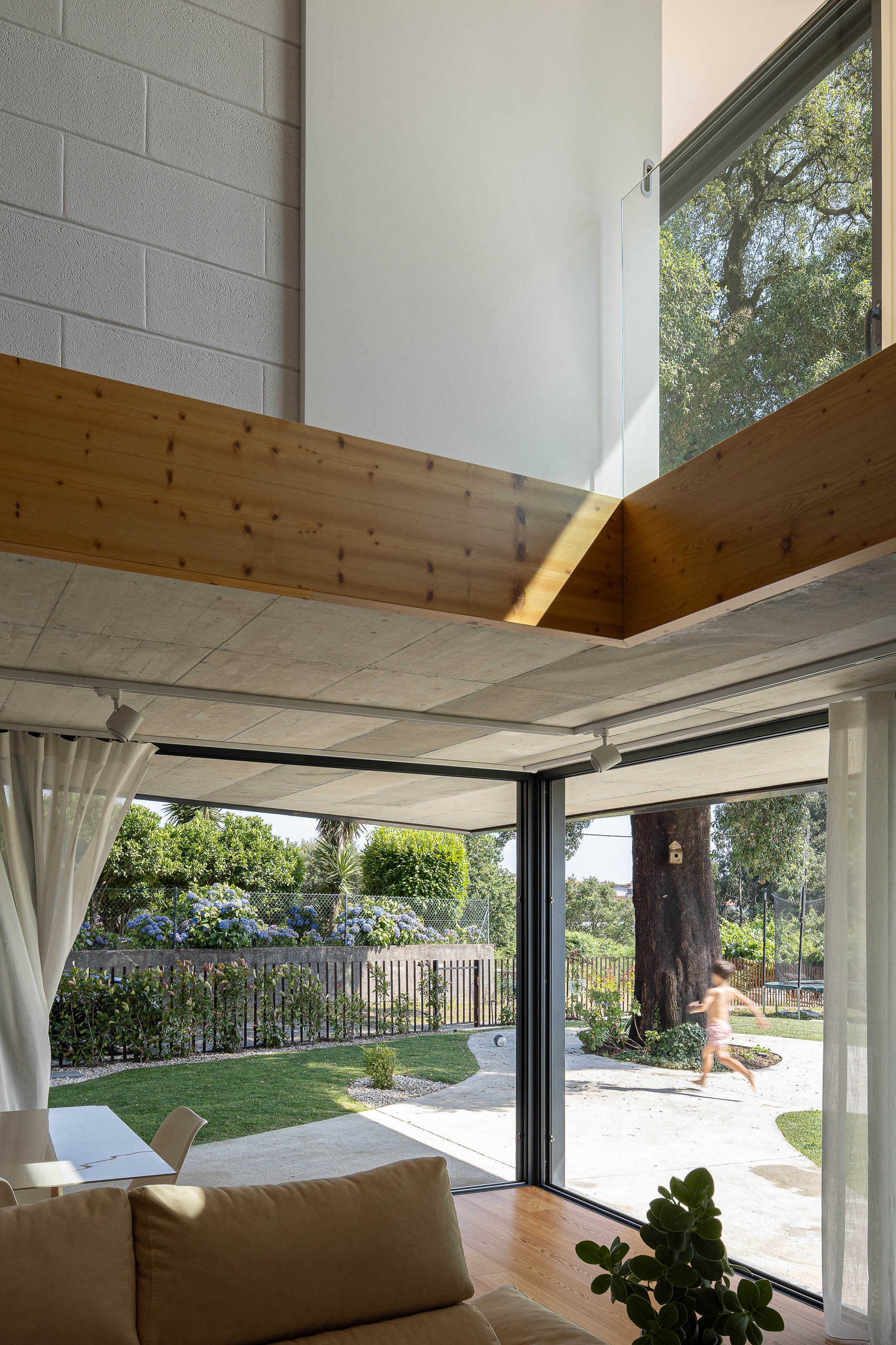 Exterior: Vista da fachada com revestimento de cortiça e tijolo, com vinhas ao fundo e criança a correr. — Casa do Sobreiro arquitetura Skemba - Arquitectura e Engenharia em Amarante