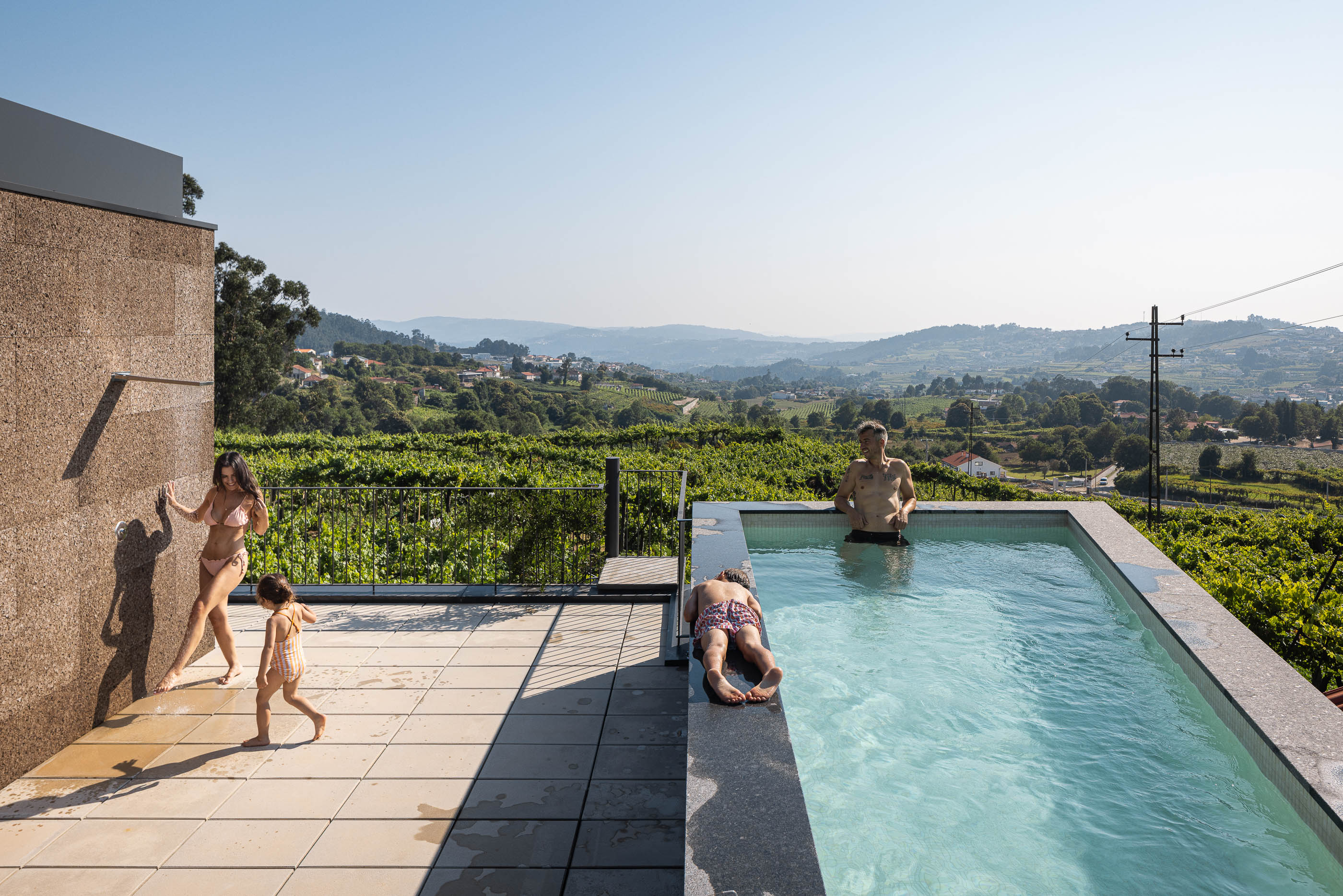 Sala de estar: Vista do corredor com cortina branca, pavimento de madeira e teto de betão aparente. — Casa do Sobreiro arquitetura Skemba - Arquitectura e Engenharia em Amarante
