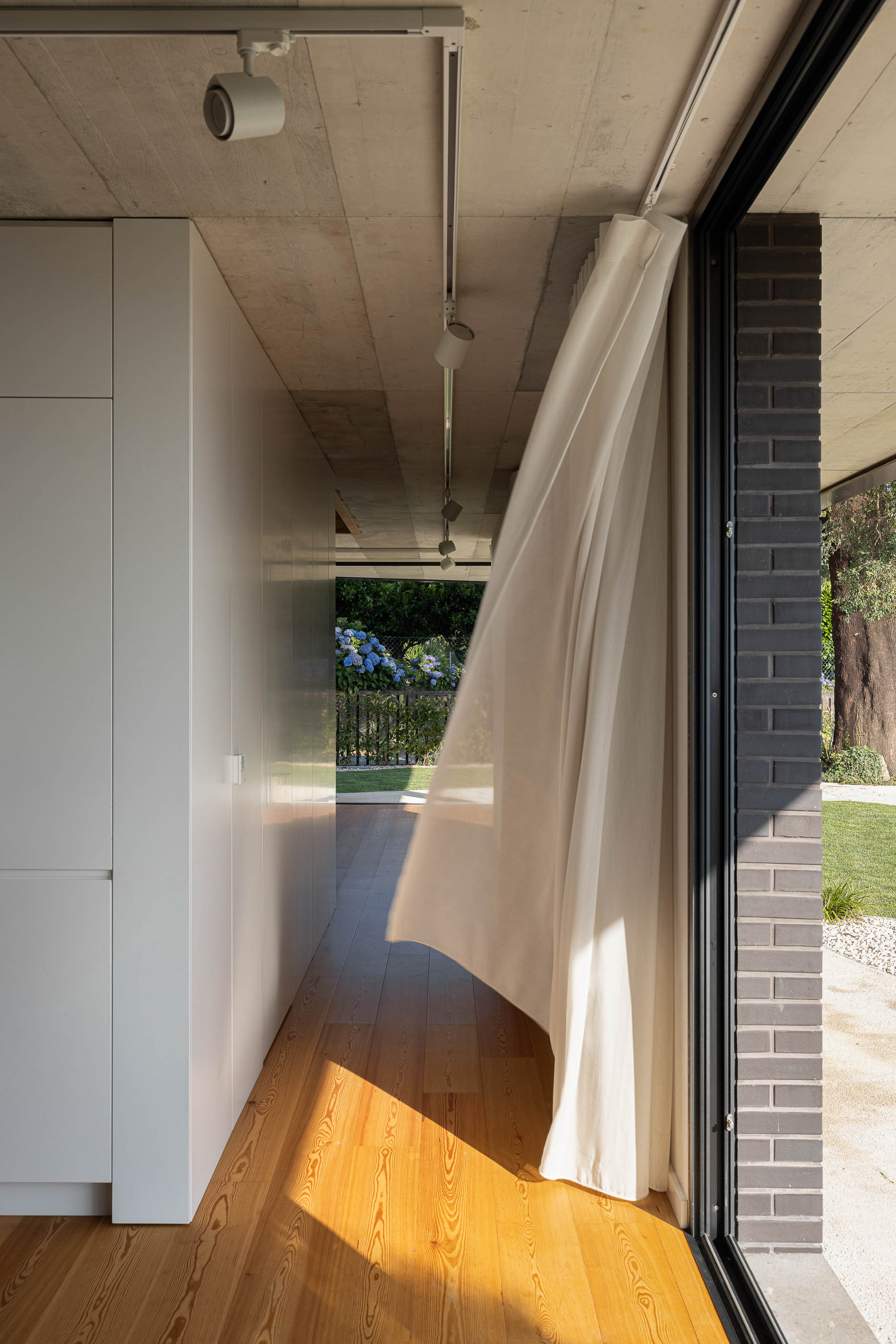 Sala de estar: Detalhe da cortina branca com vista para o jardim e vinhas. — Casa do Sobreiro arquitetura Skemba - Arquitectura e Engenharia em Amarante