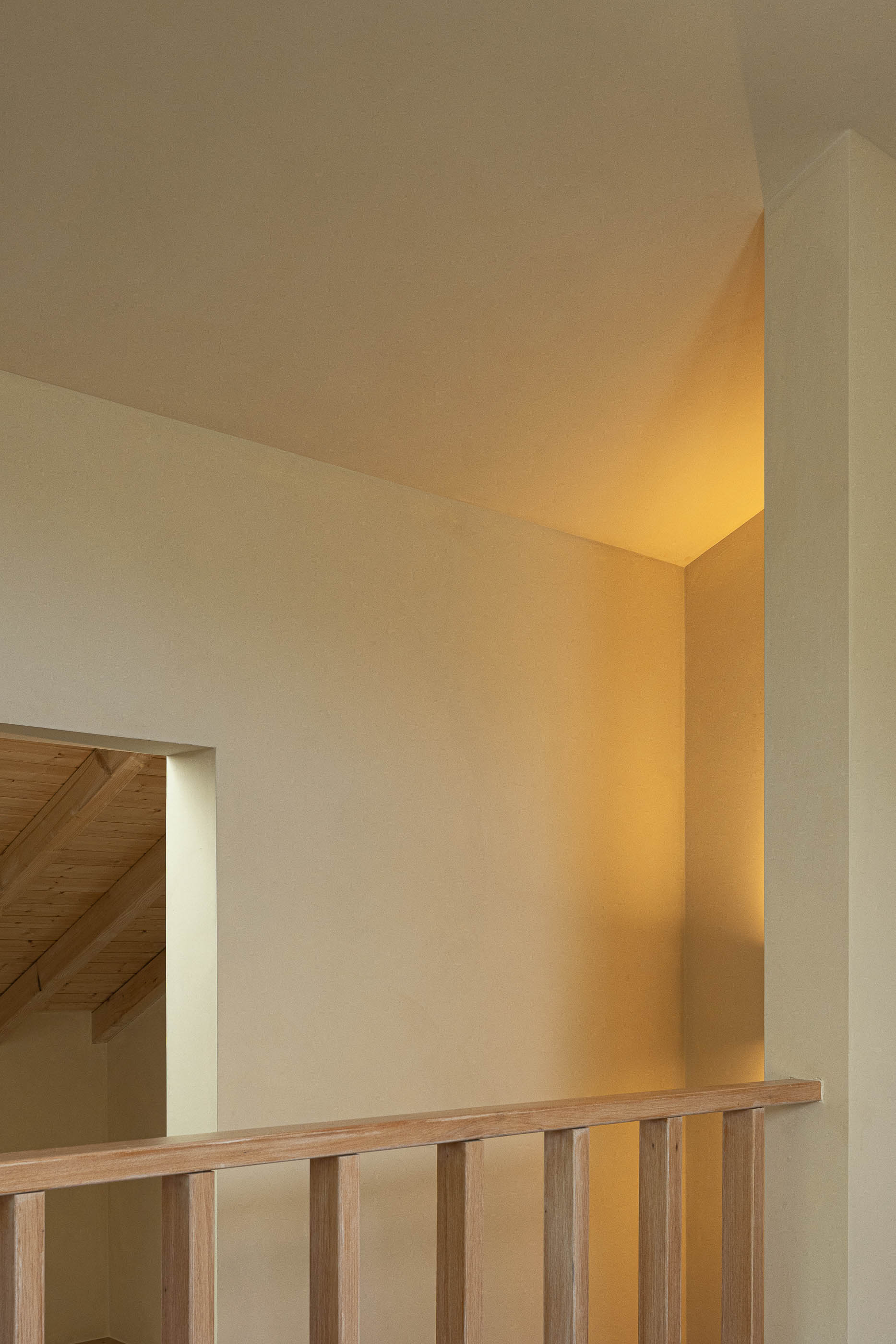 Hall: Detalhe do corrimão em madeira e iluminação indireta na parede. — Casa de Sintra arquitetura Tsou Arquitectos em Sintra