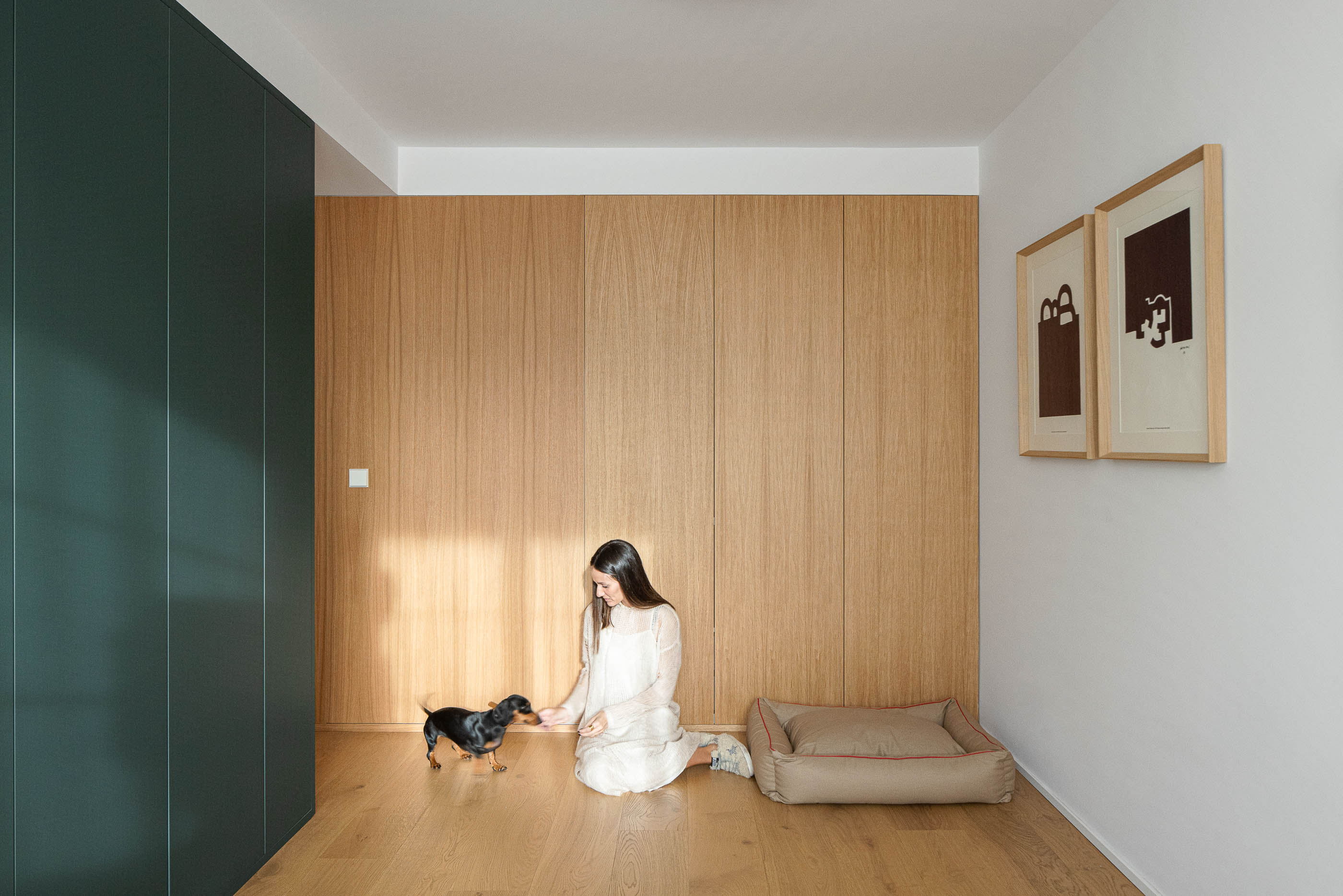 Quarto com cama de casal, cabeceira verde escura e roupeiro verde escuro. Pavimento em madeira clara e quadros na parede. — Reforma Apartamento CV em Avilés arquitetura David Olmos Arquitectos em Avilés