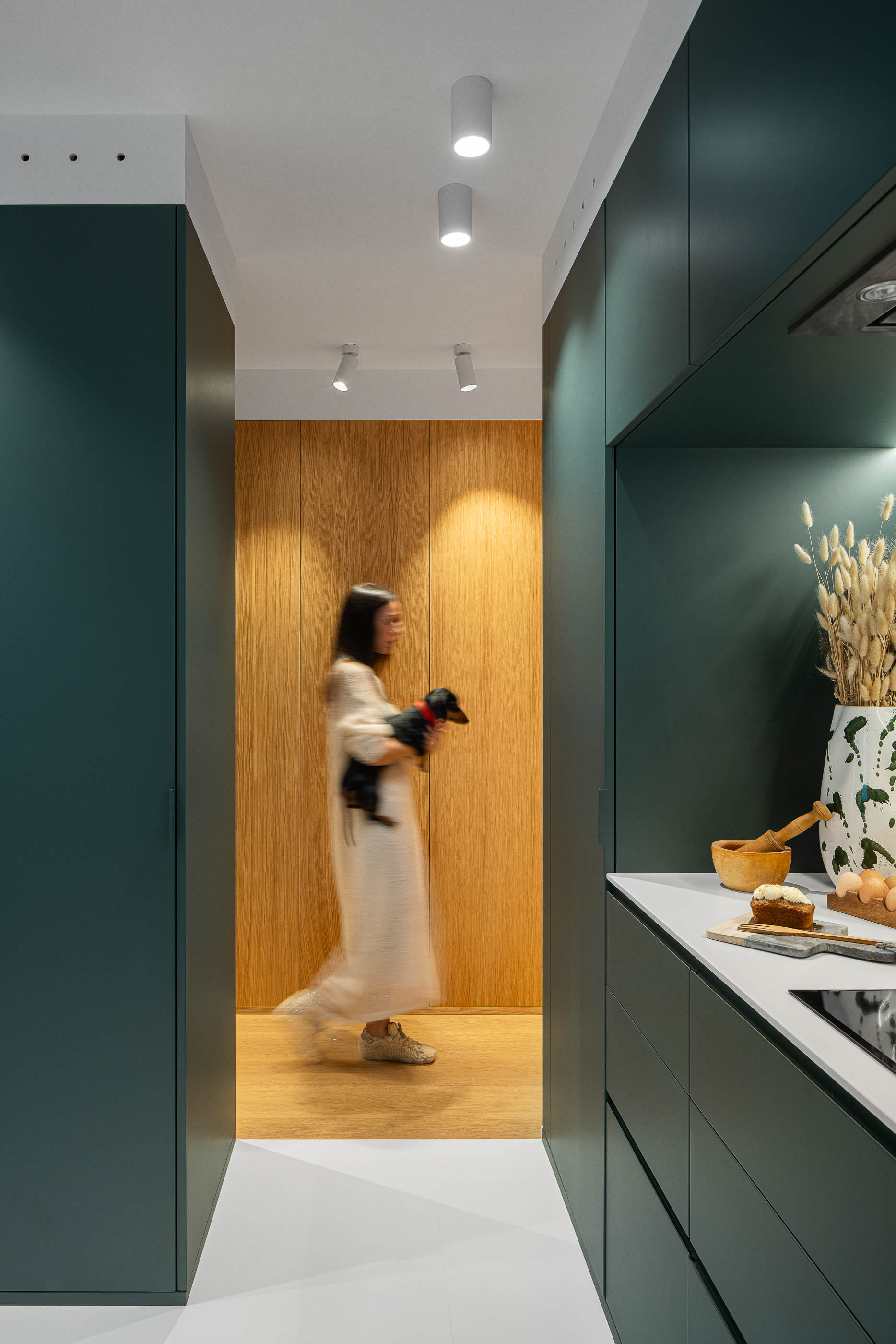 Cozinha com armários verdes escuros e pavimento branco. Porta de madeira clara para o corredor. — Reforma Apartamento CV em Avilés arquitetura David Olmos Arquitectos em Avilés