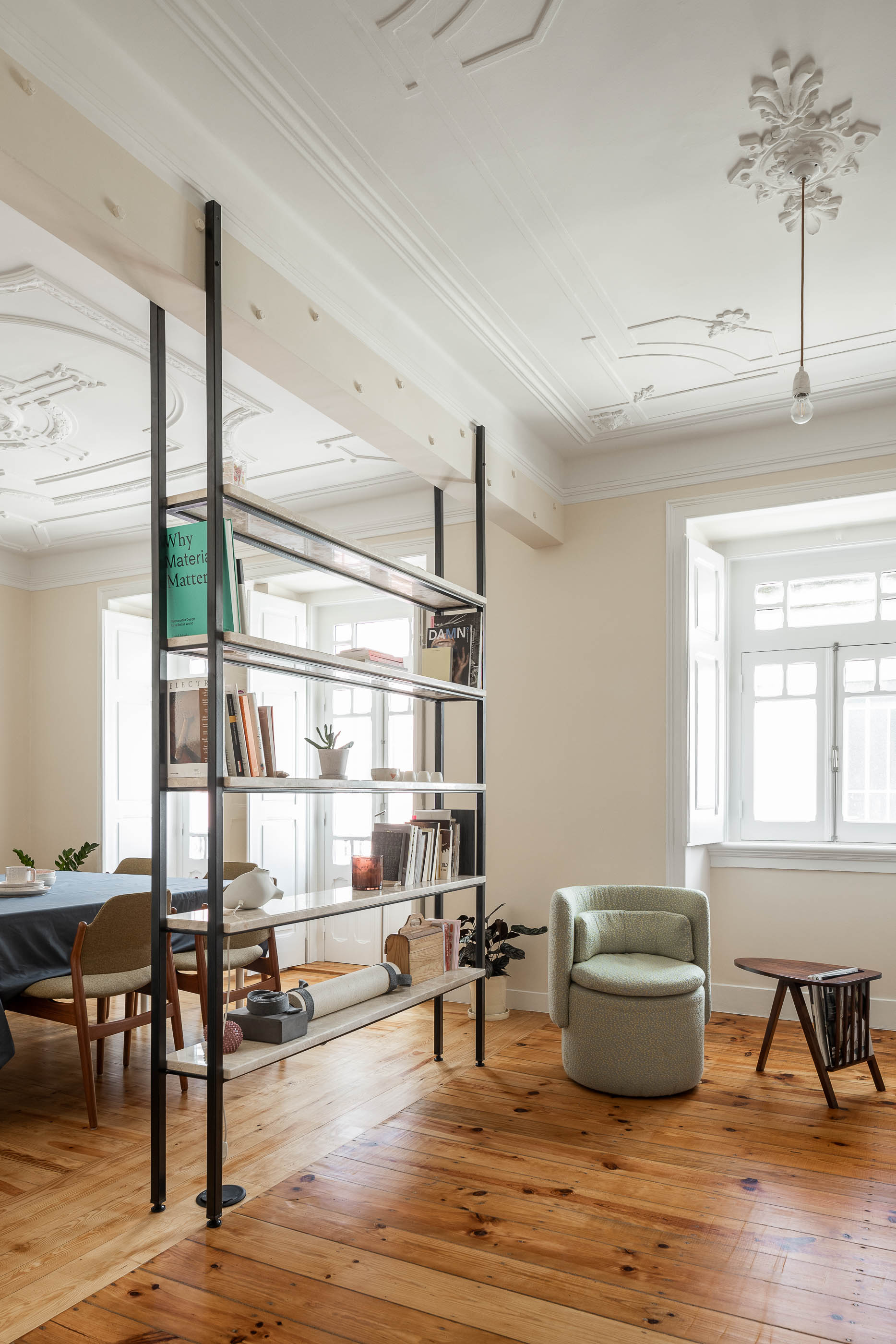 Sala: Estante metálica com prateleiras em pedra, pavimento em madeira, tecto trabalhado, cadeirão verde texturizado. — Apartamento da Penha arquitetura Paulo Moreira Architectures em Lisboa