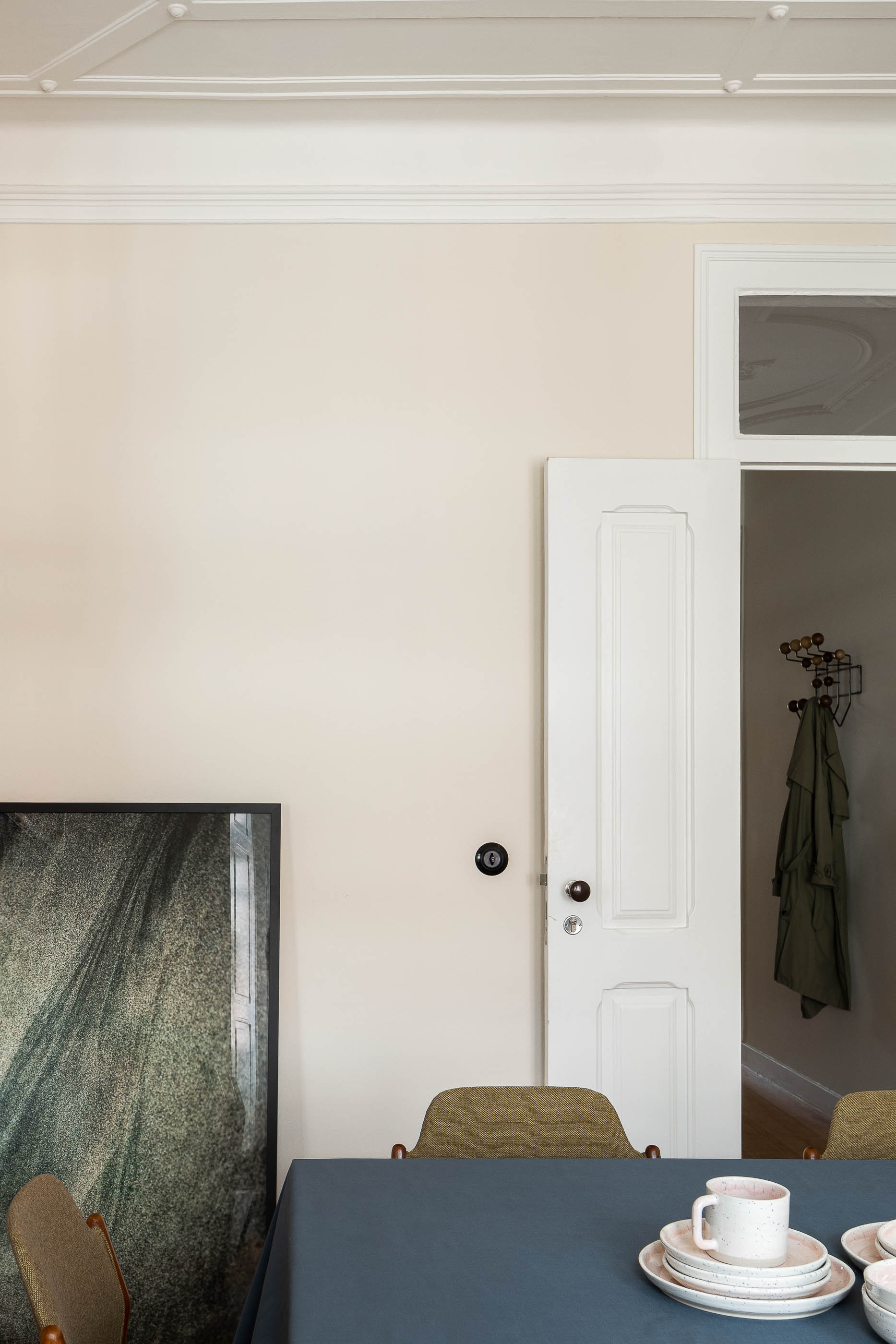 Sala de jantar: Mesa de jantar com cadeiras, porta branca para corredor, quadro na parede. — Apartamento da Penha arquitetura Paulo Moreira Architectures em Lisboa