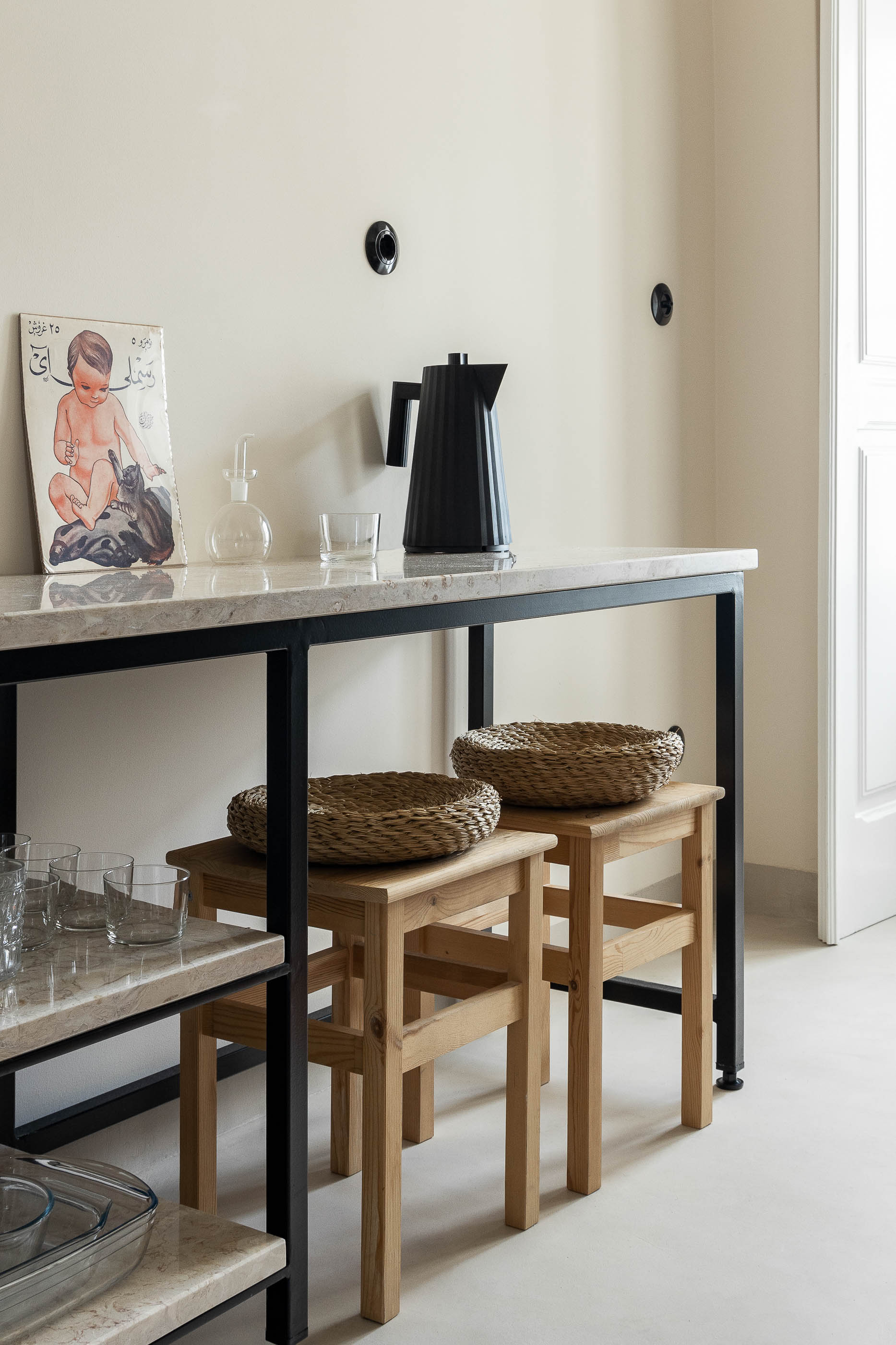 Cozinha: Bancada em pedra com estrutura metálica, cadeiras de madeira, pavimento claro. — Apartamento da Penha arquitetura Paulo Moreira Architectures em Lisboa