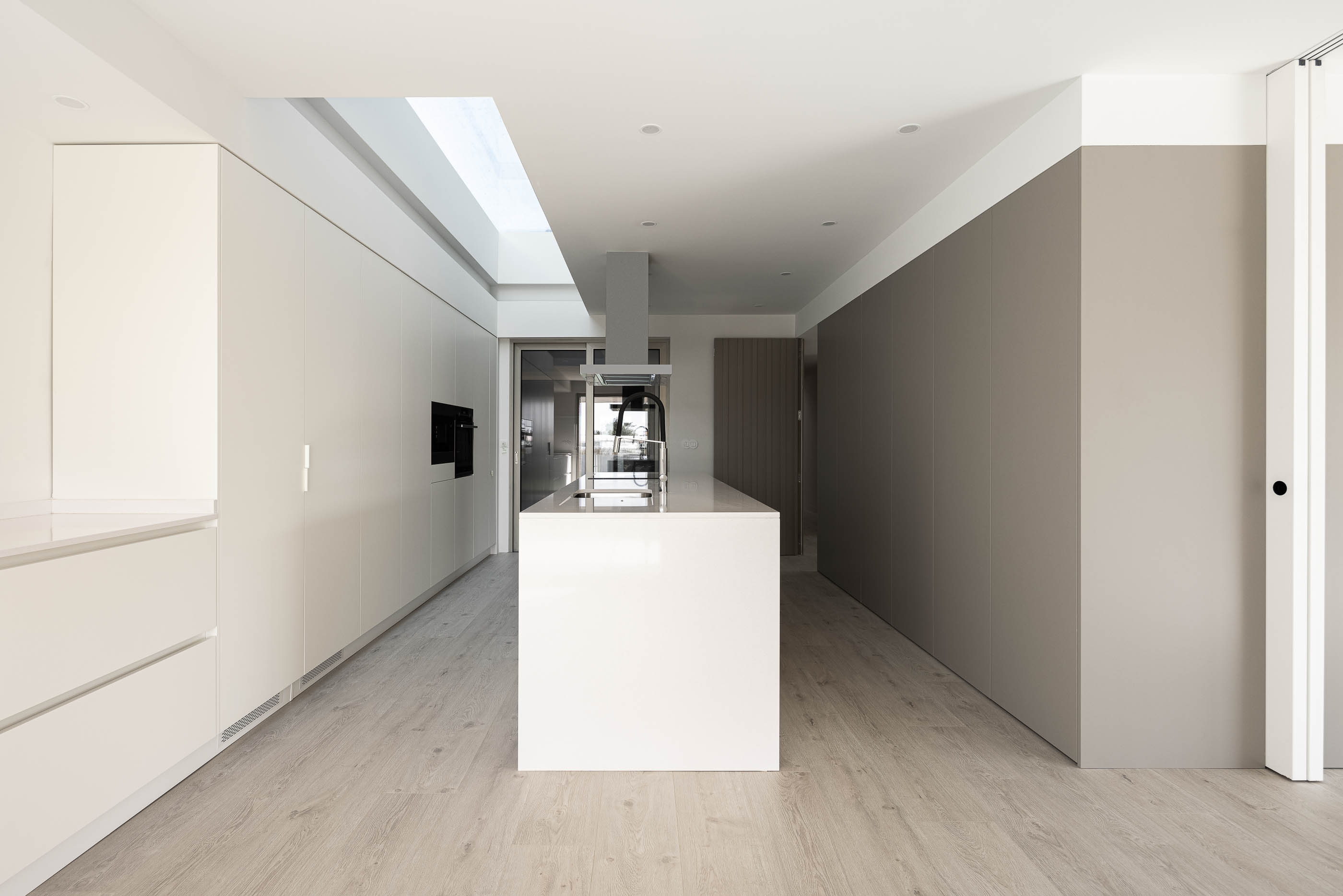 Fachada: Detalhe da estrutura em betão, tijolo e vidro, com relvado e vegetação ao fundo. — Casa HC arquitetura Sónia Cruz Arquitectura em Aveiro