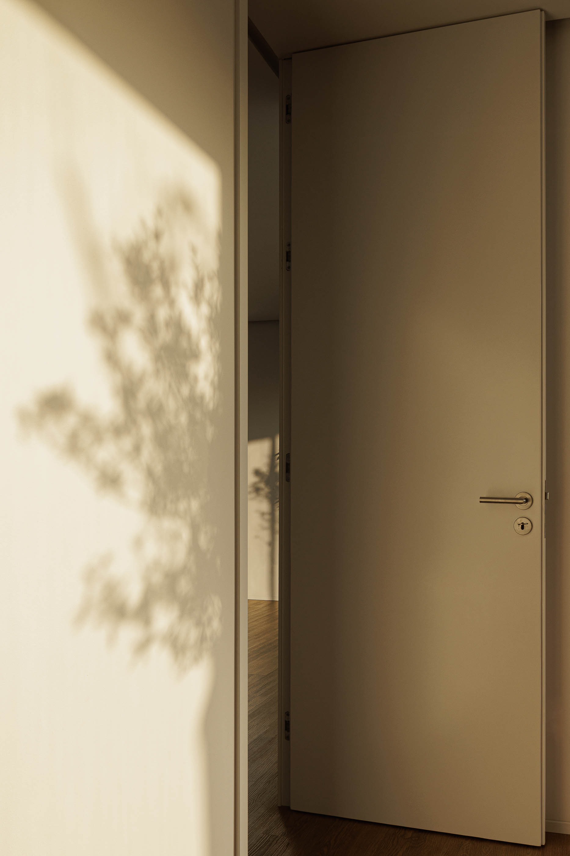 Interior: Porta interior branca entreaberta, com pavimento em madeira e sombra de árvore na parede. — Casa AS arquitetura Mário Alves Arquitecto em Santa Maria da Feira