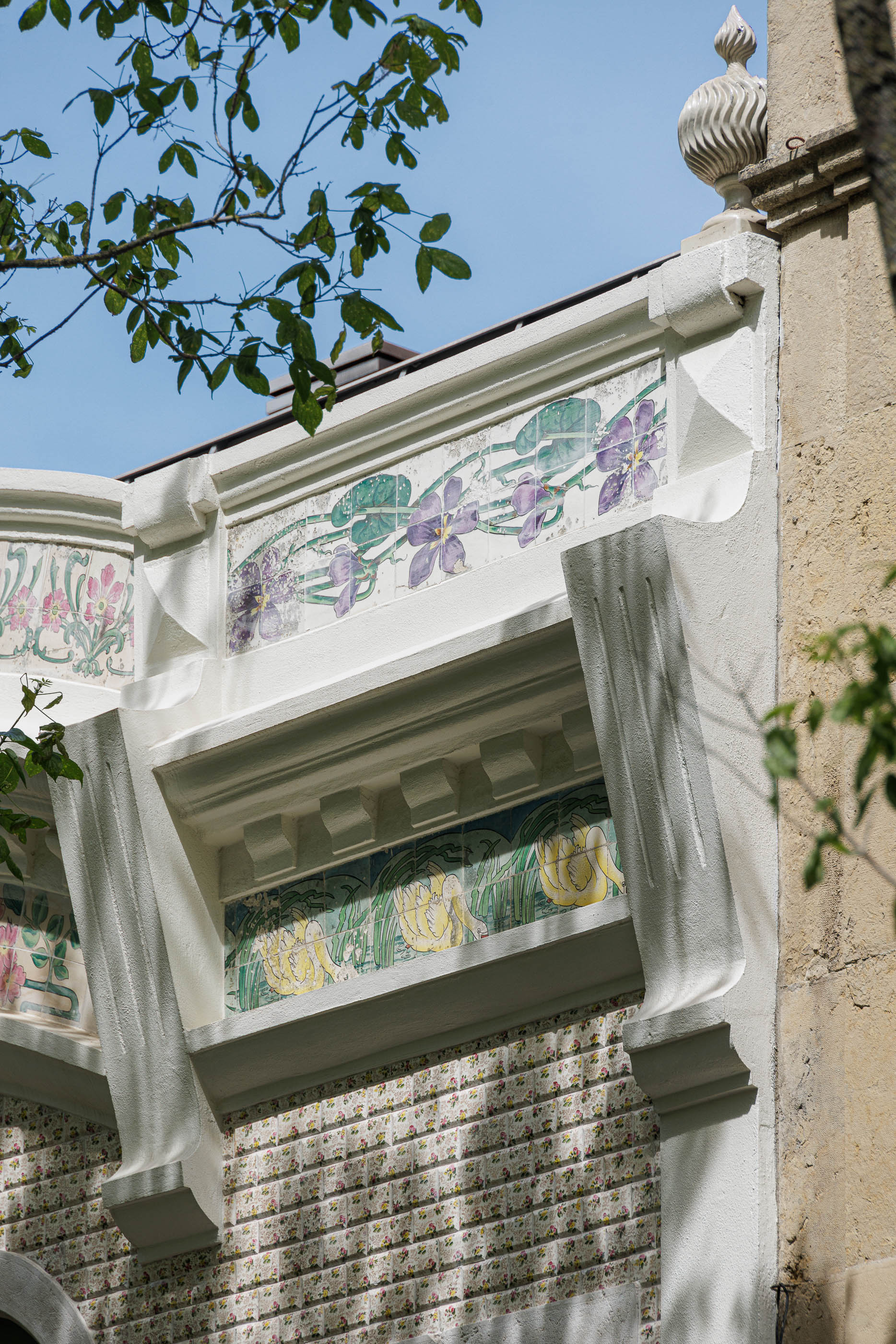 Fachada: Detalhe da cornija com azulejos decorativos florais em tons de roxo, verde e amarelo. — Possidónio da Silva 37 arquitetura Fragmentos em Lisboa