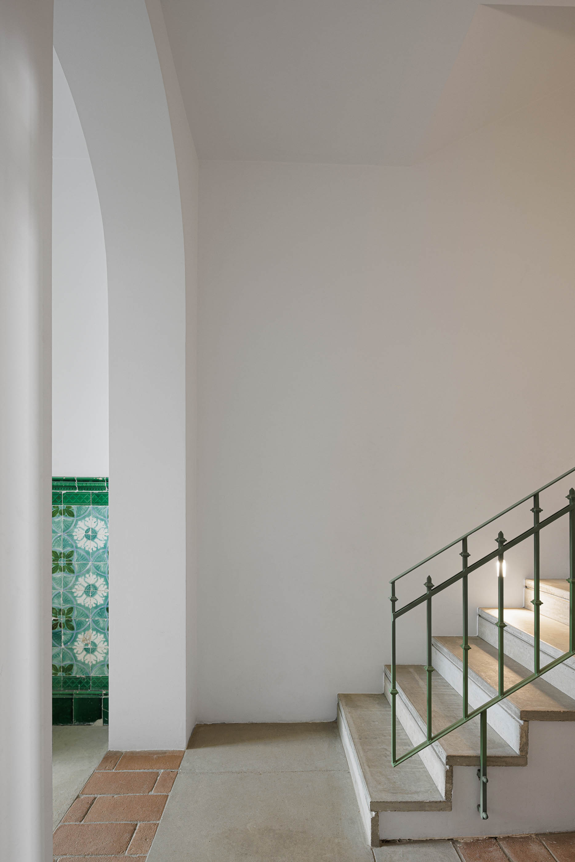 Escadas: Degraus em pedra e corrimão verde, com painel de azulejos visível ao fundo. — Possidónio da Silva 37 arquitetura Fragmentos em Lisboa