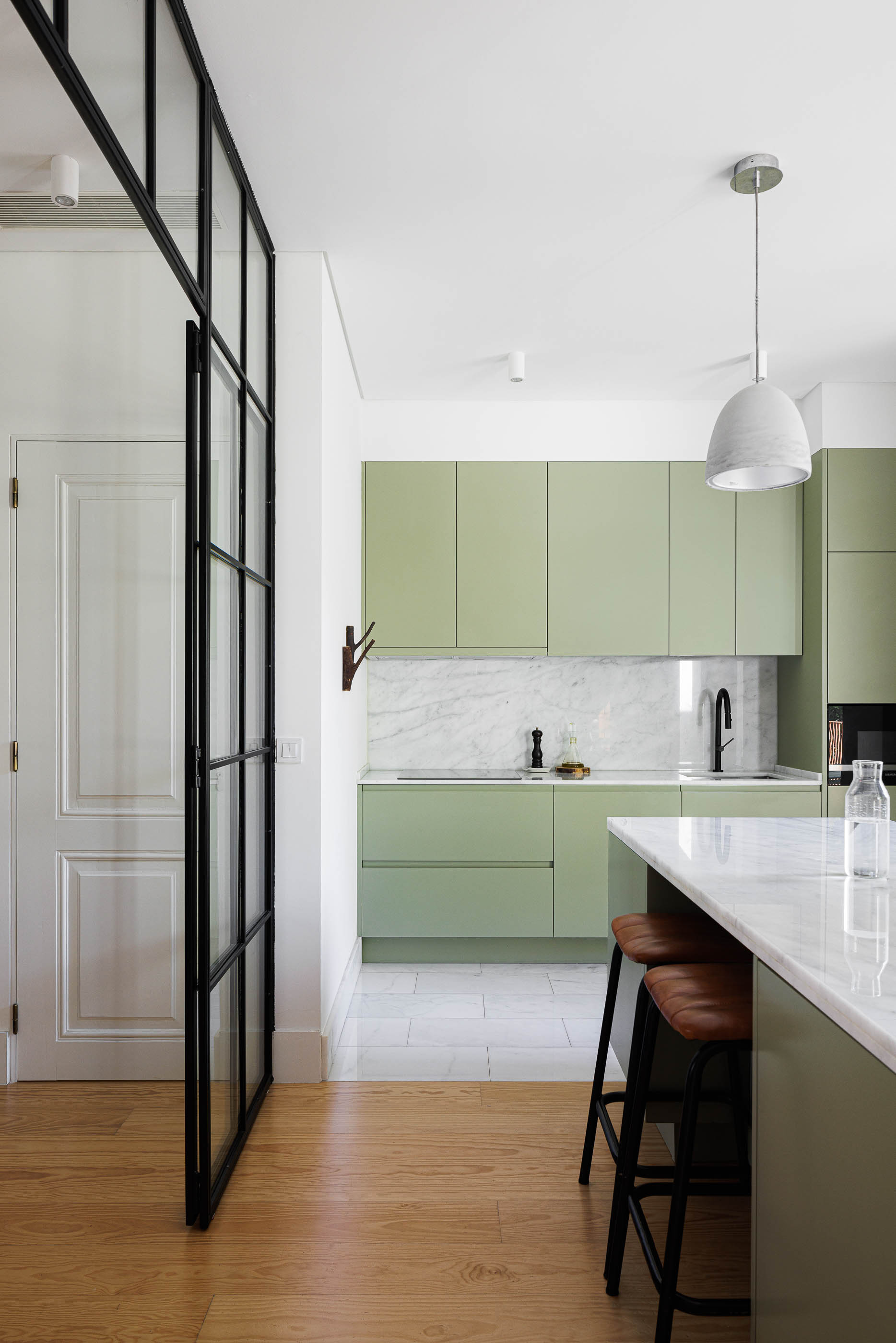 Cozinha: Armários verde-água, bancada em mármore branco, pavimento claro e divisória de vidro. — Possidónio da Silva 37 arquitetura Fragmentos em Lisboa