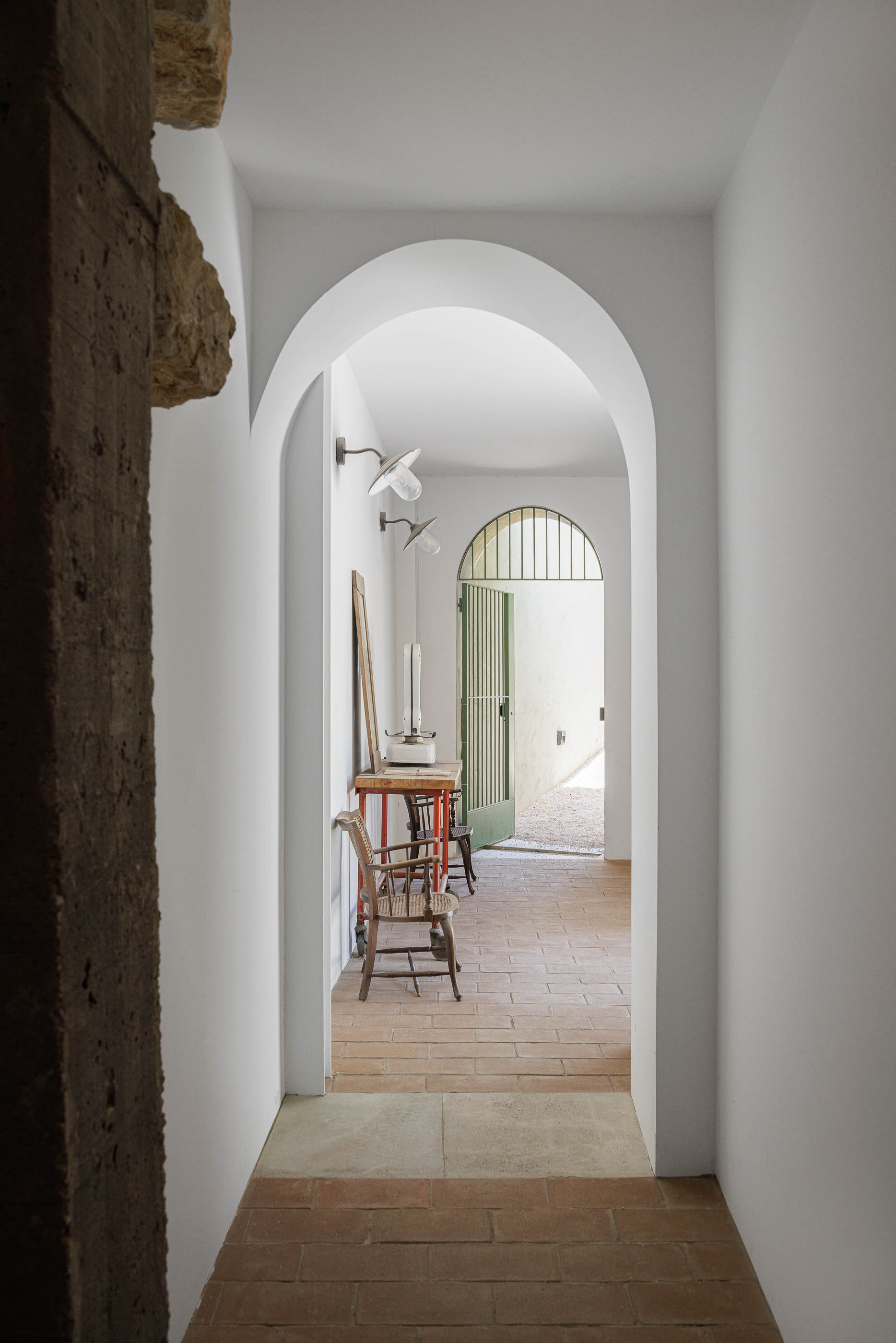 Corredor: Arco branco, pavimento em tijoleira e móveis antigos, com porta verde ao fundo. — Possidónio da Silva 37 arquitetura Fragmentos em Lisboa
