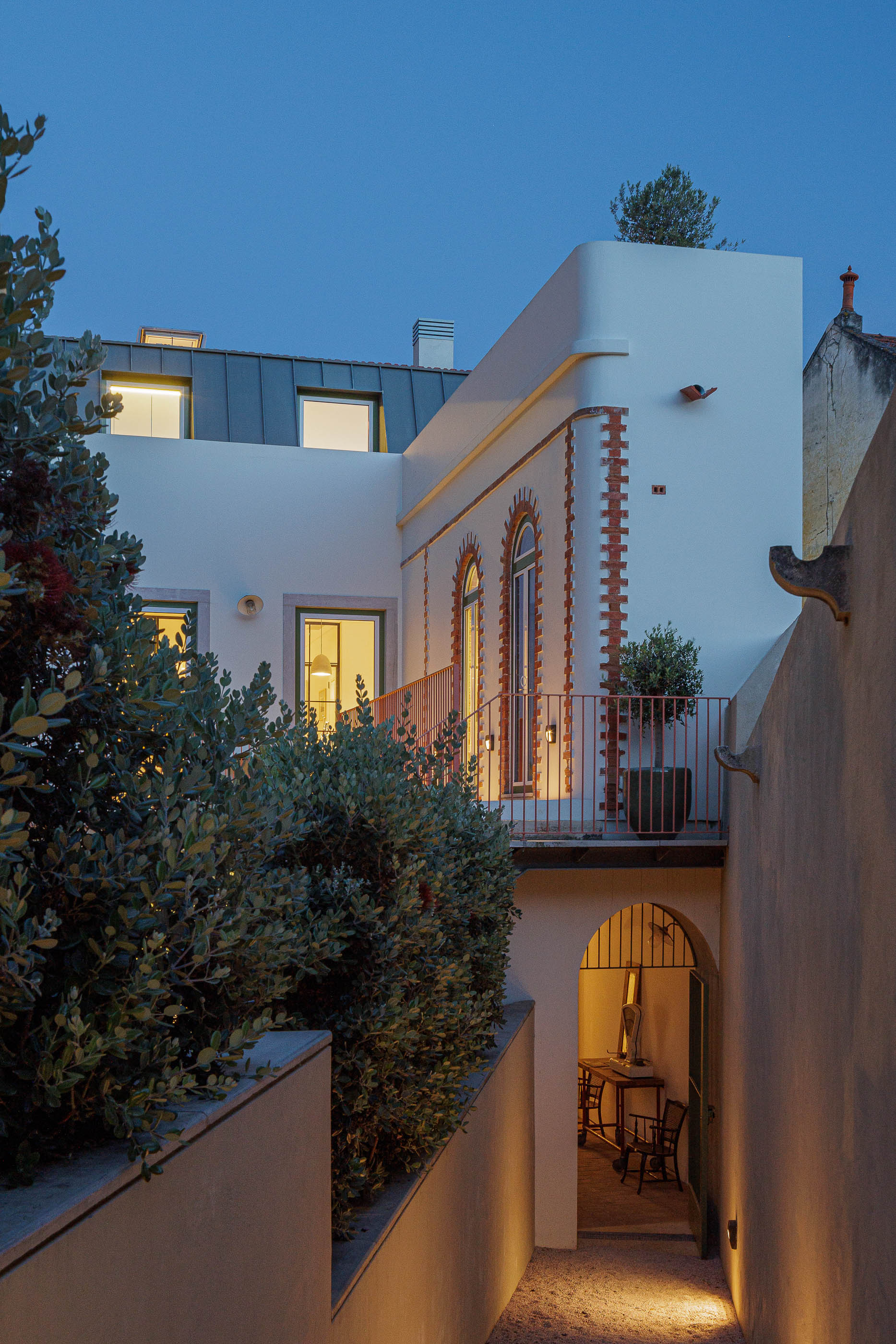 Exterior: Vista noturna da casa com terraço, escadas cor de tijolo e vegetação. — Possidónio da Silva 37 arquitetura Fragmentos em Lisboa