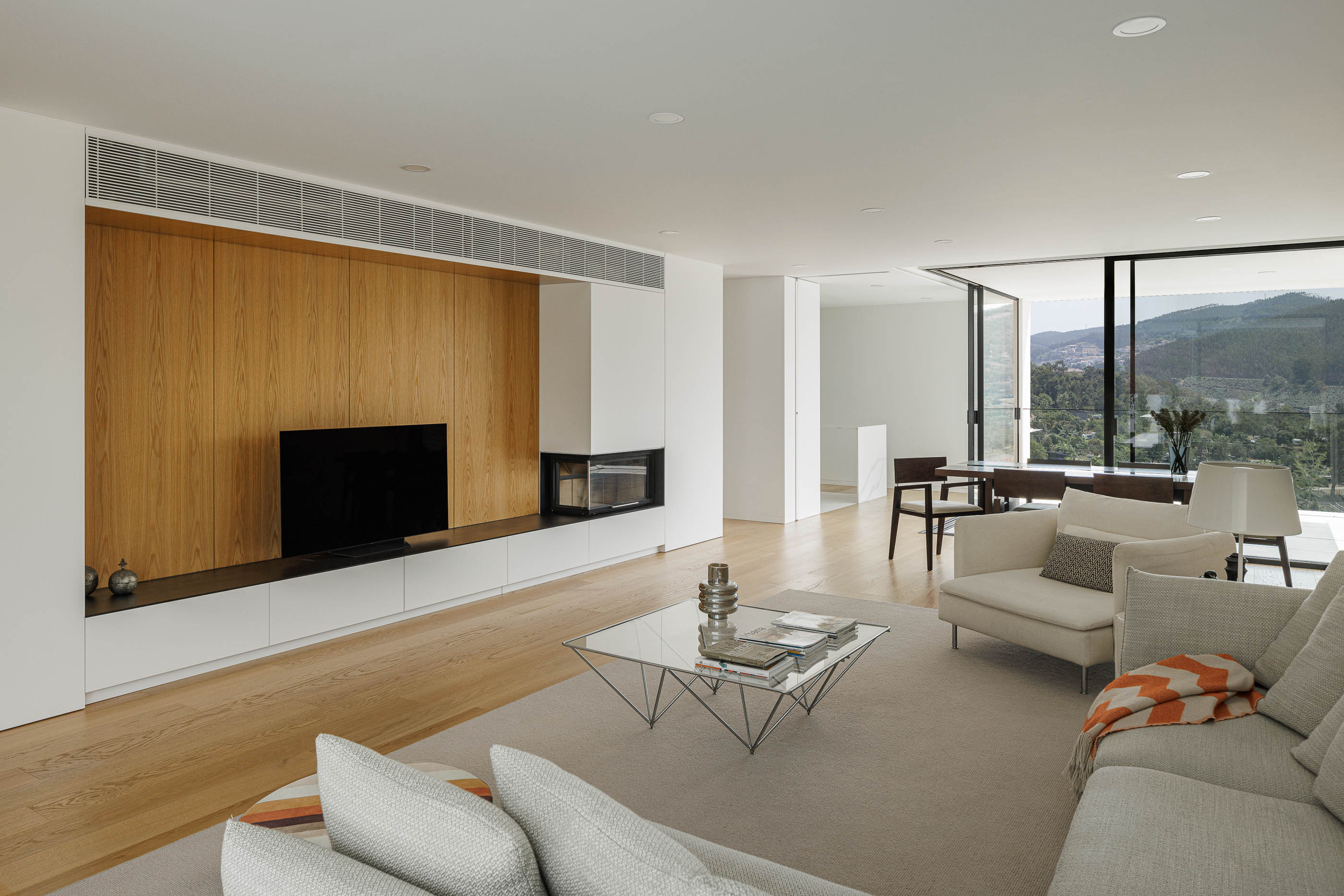 Sala de estar com móvel de madeira e lareira. Pavimento em madeira clara e alcatifa bege. — Casa JC arquitetura Mário Alves Arquitecto em Coimbra