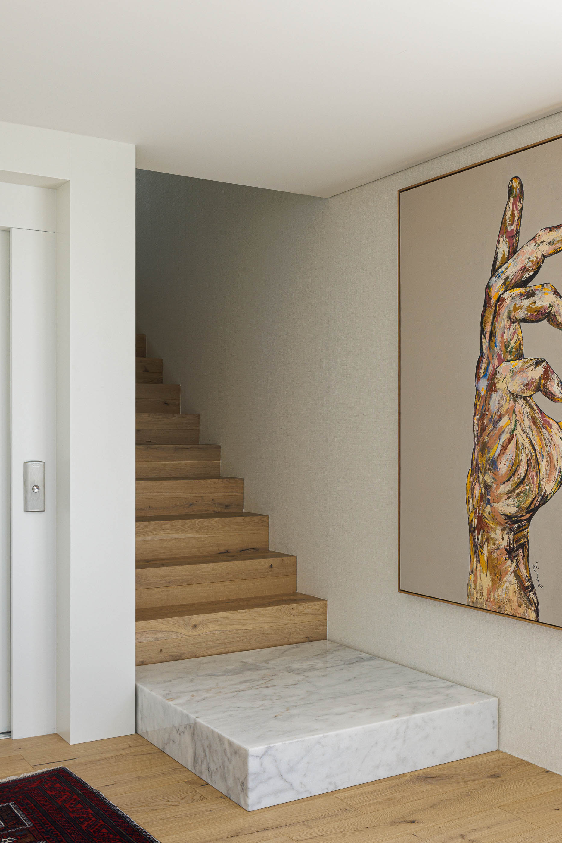 Escadas: Degraus em madeira sobre base de mármore, com pintura moderna na parede. — CASA [EN]COSTA arquitetura Hous3 em Guimarães