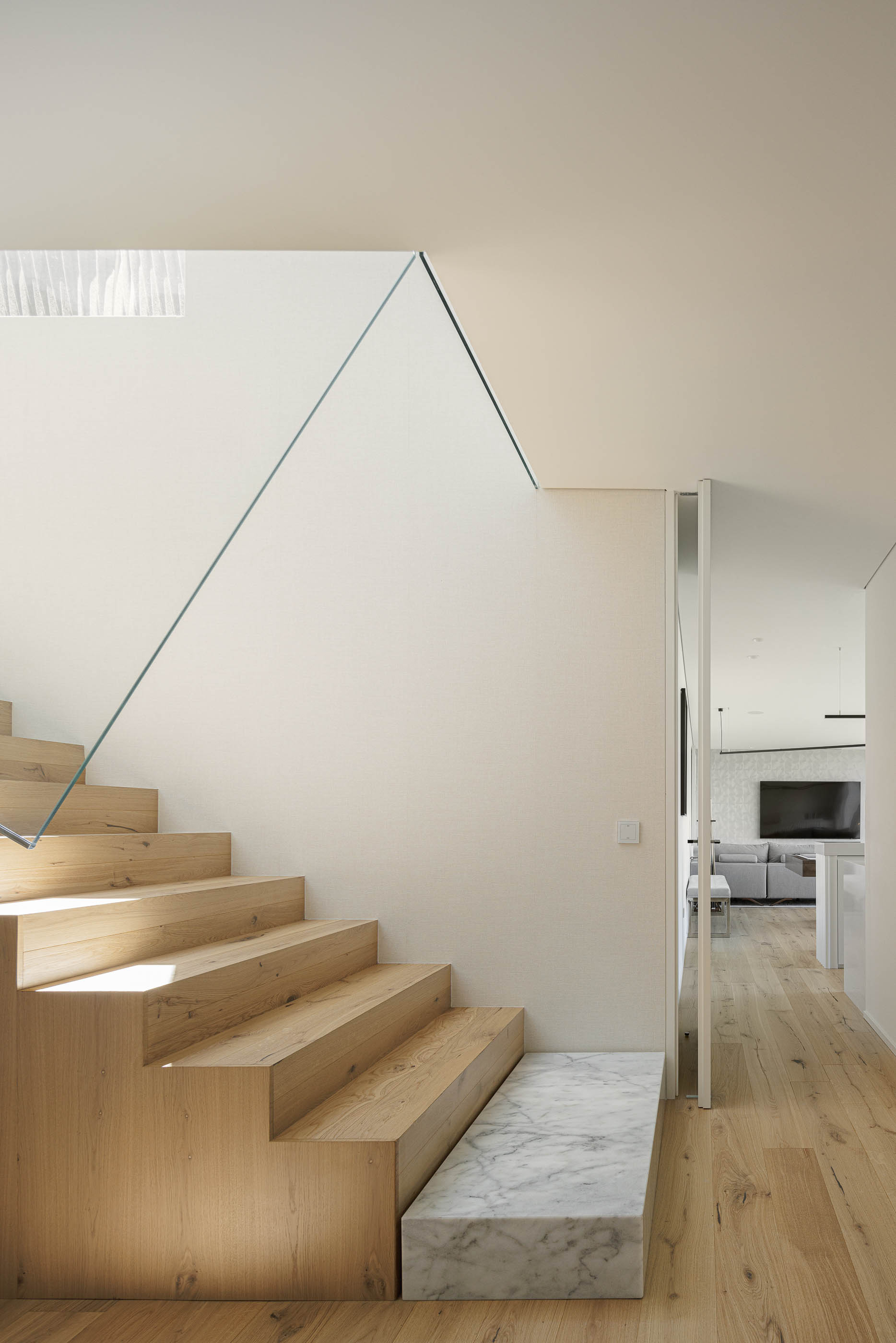 Escadas: Escadas de madeira com guarda em vidro, pavimento em madeira clara e vista para a sala. — CASA [EN]COSTA arquitetura Hous3 em Guimarães