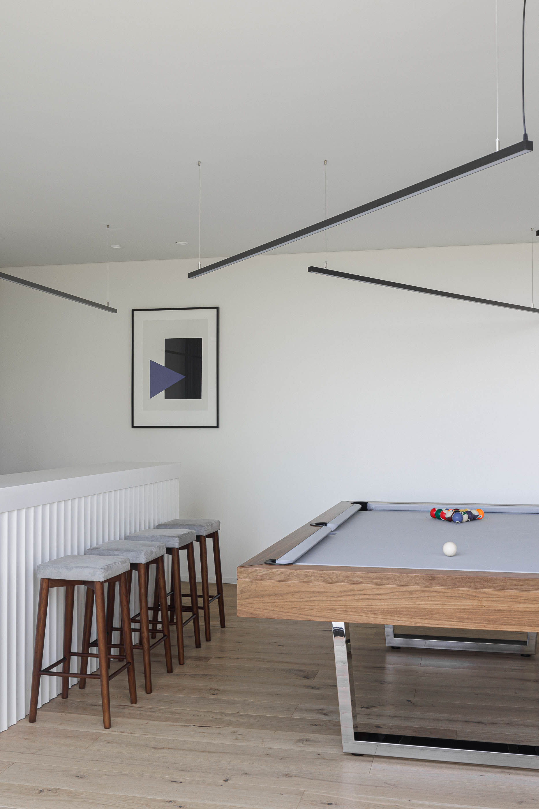 Sala de jogos: Mesa de bilhar com estrutura em madeira e cadeiras altas estofadas em cinza. — CASA [EN]COSTA arquitetura Hous3 em Guimarães