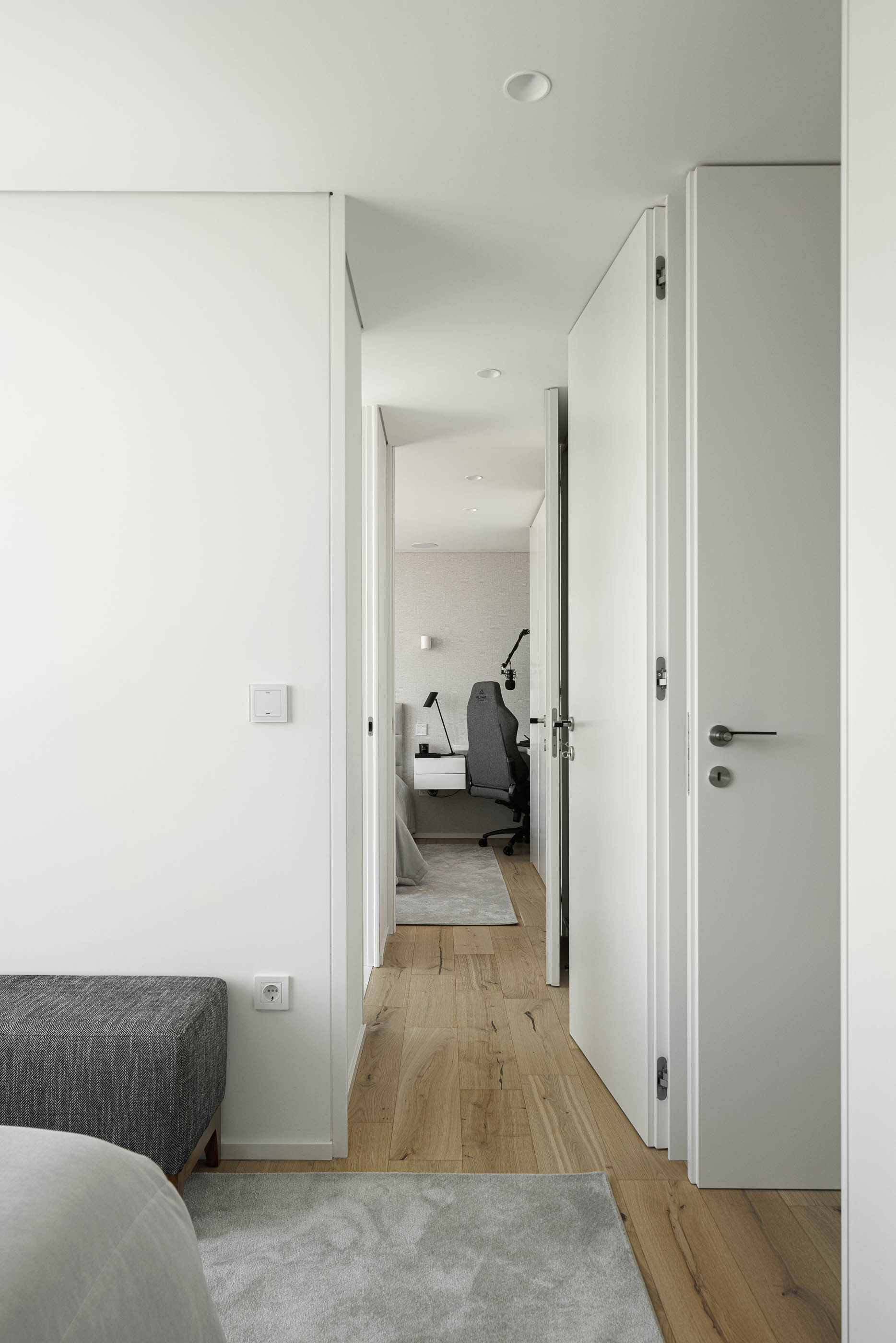 Quarto: Perspectiva do quarto para a zona de secretária, com pavimento em madeira clara. — CASA [EN]COSTA arquitetura Hous3 em Guimarães