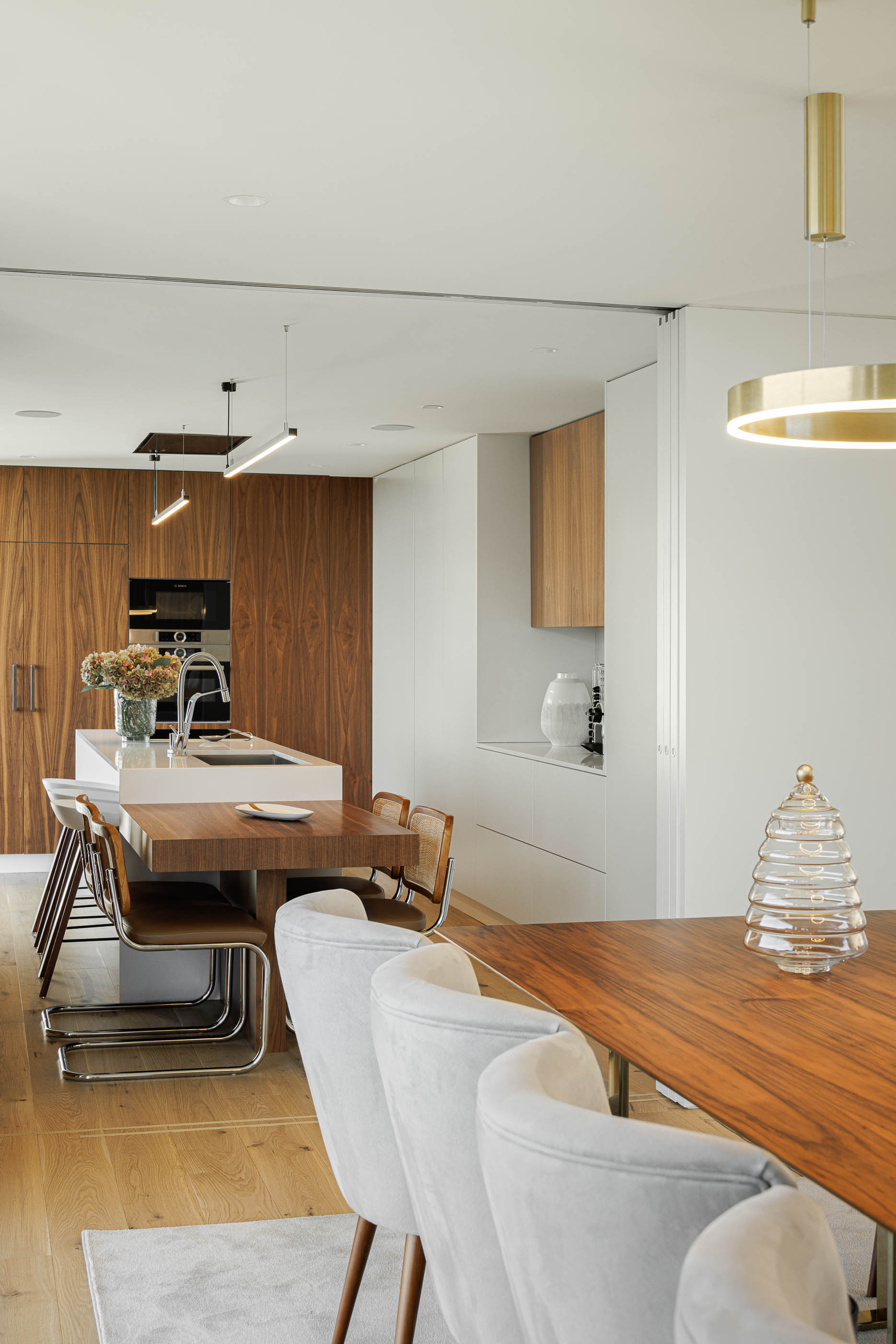 Cozinha/Sala de jantar: Mesa de jantar em madeira com cadeiras modernas, armários em madeira escura. — CASA [EN]COSTA arquitetura Hous3 em Guimarães