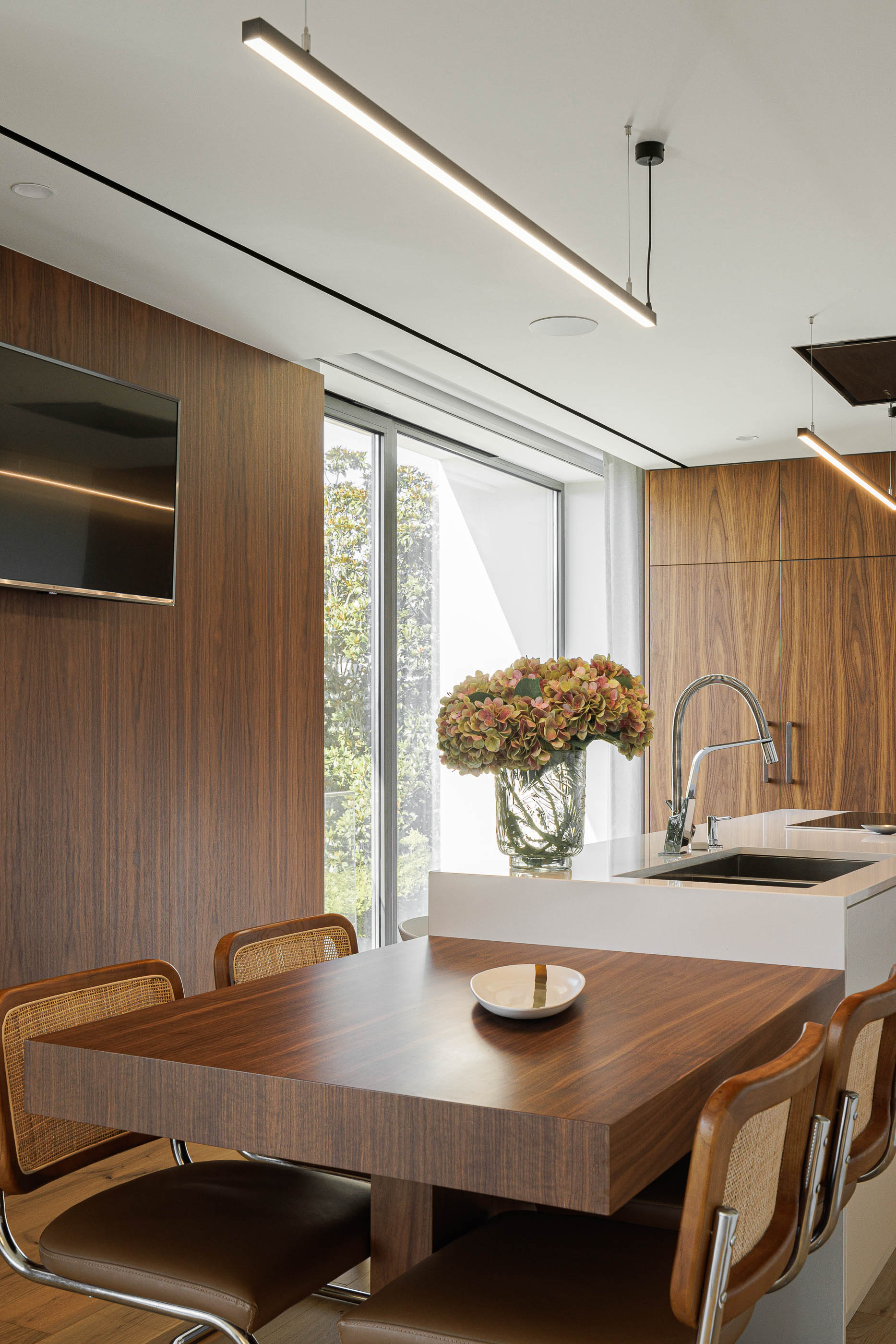 Cozinha/Sala de jantar: Detalhe da mesa de jantar com cadeiras em madeira e vista para a janela. — CASA [EN]COSTA arquitetura Hous3 em Guimarães