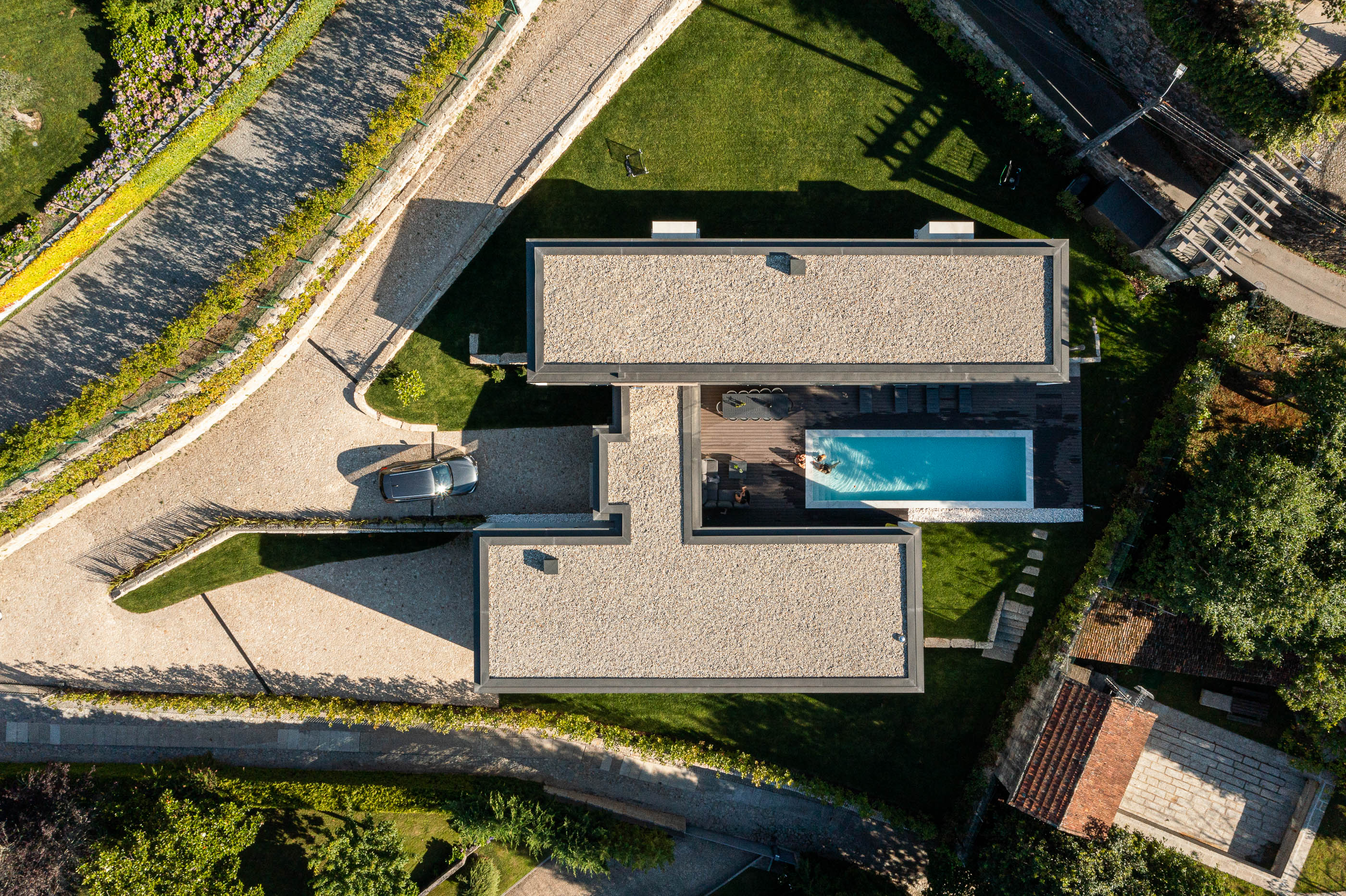 Exterior: Vista aérea da casa com piscina, deck em madeira, jardim e acesso em calçada. — CASA [EN]COSTA arquitetura Hous3 em Guimarães