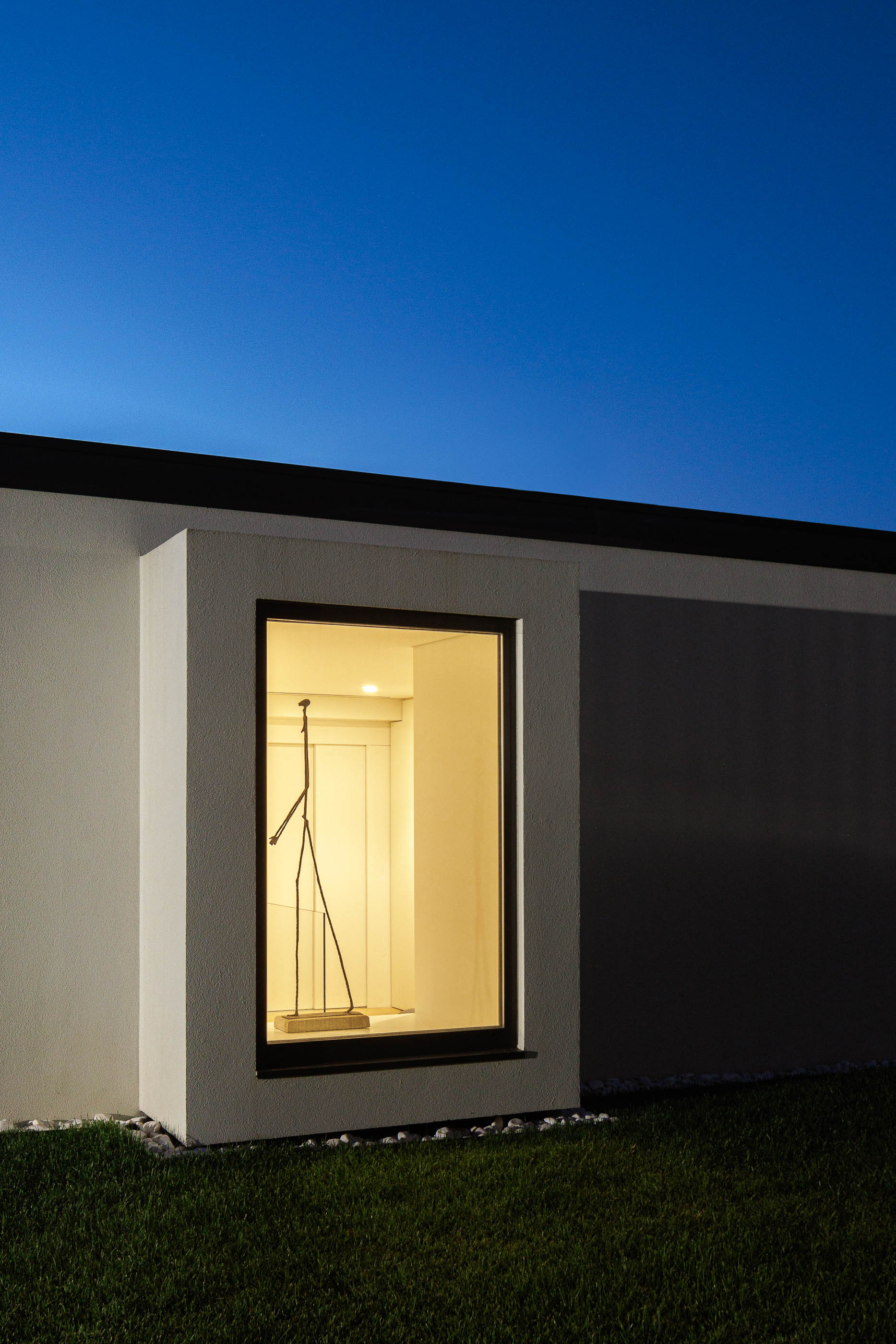 Exterior: Detalhe da janela com escultura iluminada, embutida na fachada branca. — CASA [EN]COSTA arquitetura Hous3 em Guimarães