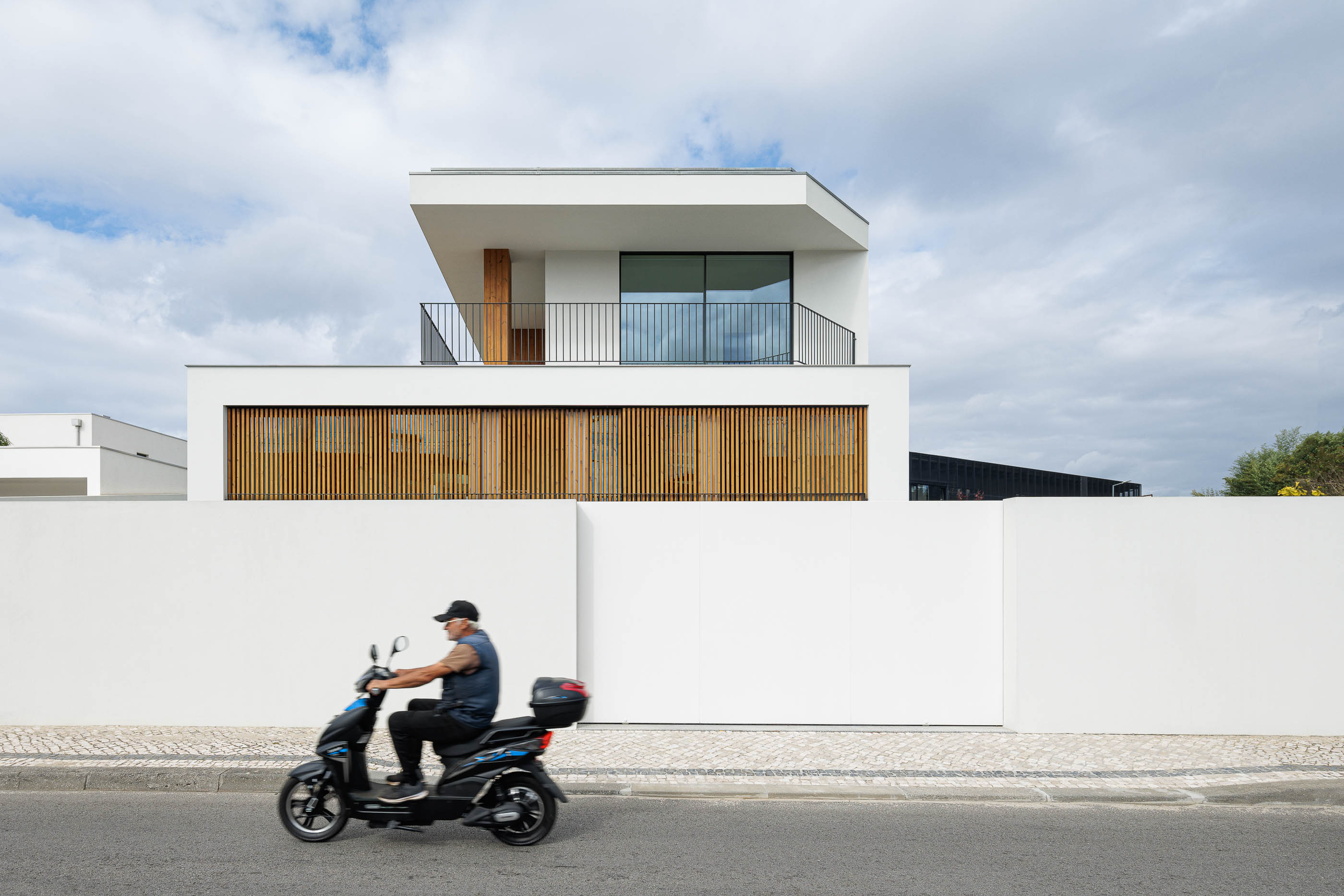 Fachada: Casa branca de dois andares com detalhes em madeira e varanda com grade preta. — Casa R.P. arquitetura Atelier d´Arquitectura Lopes da Costa em Santa Maria da Feira